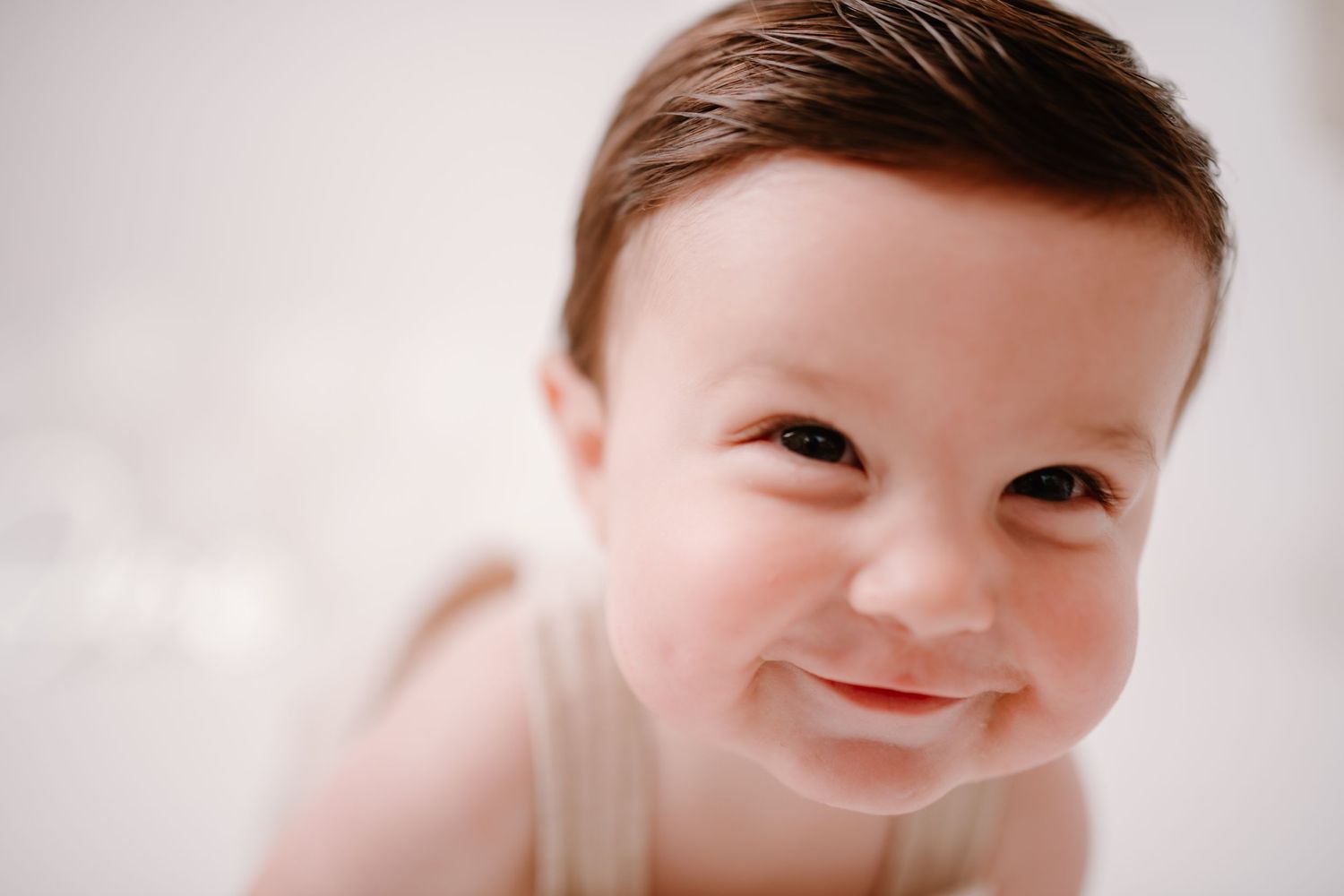 Close-up portrait of smiling child wearing light colored clothing.