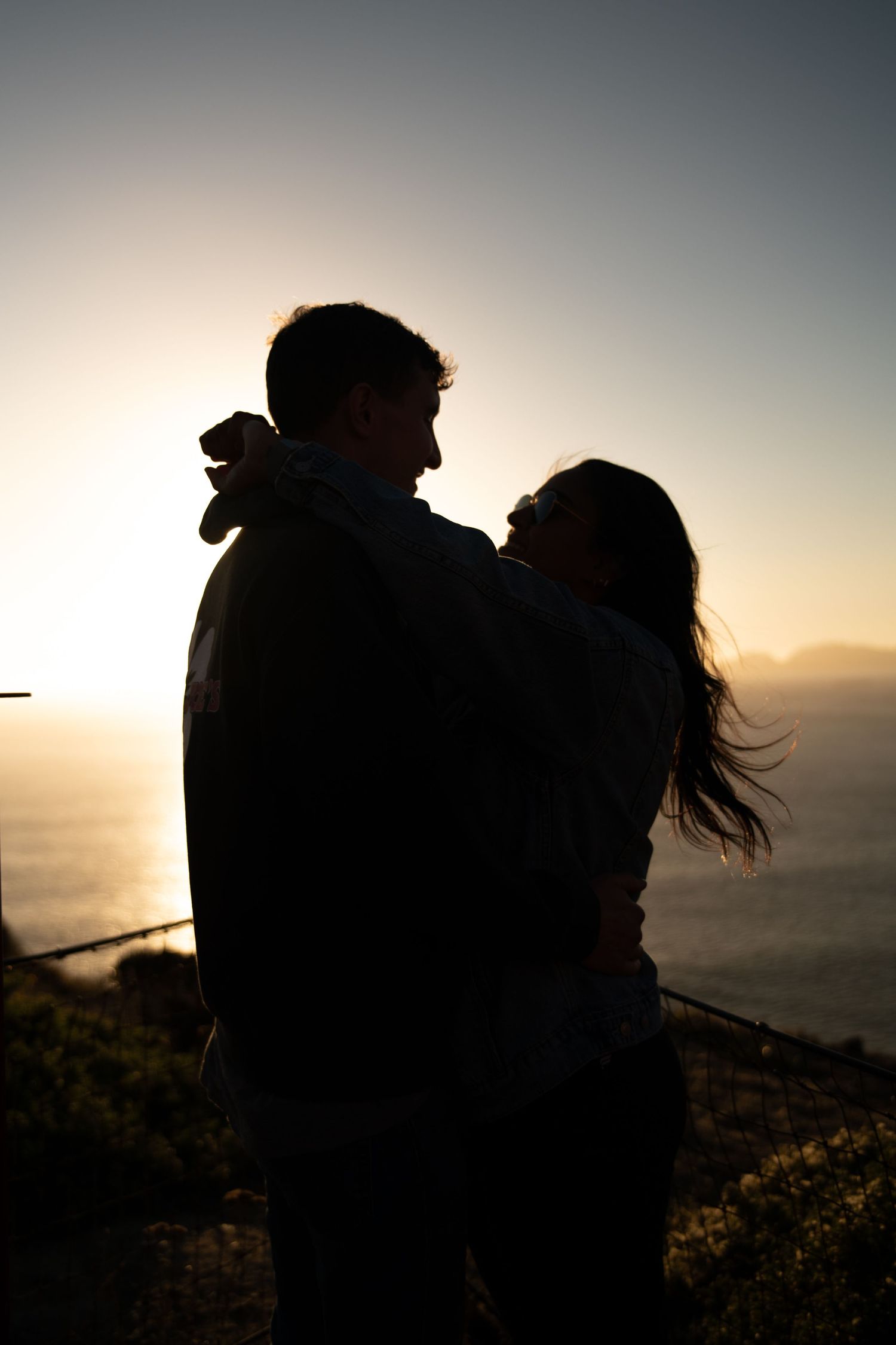 A silhouetted couple embracing against a dramatic sunset sky.