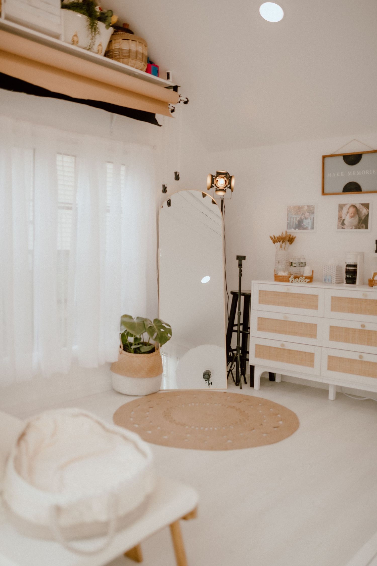 Clean white photography studio with lighting equipment, furniture and decorative accents.