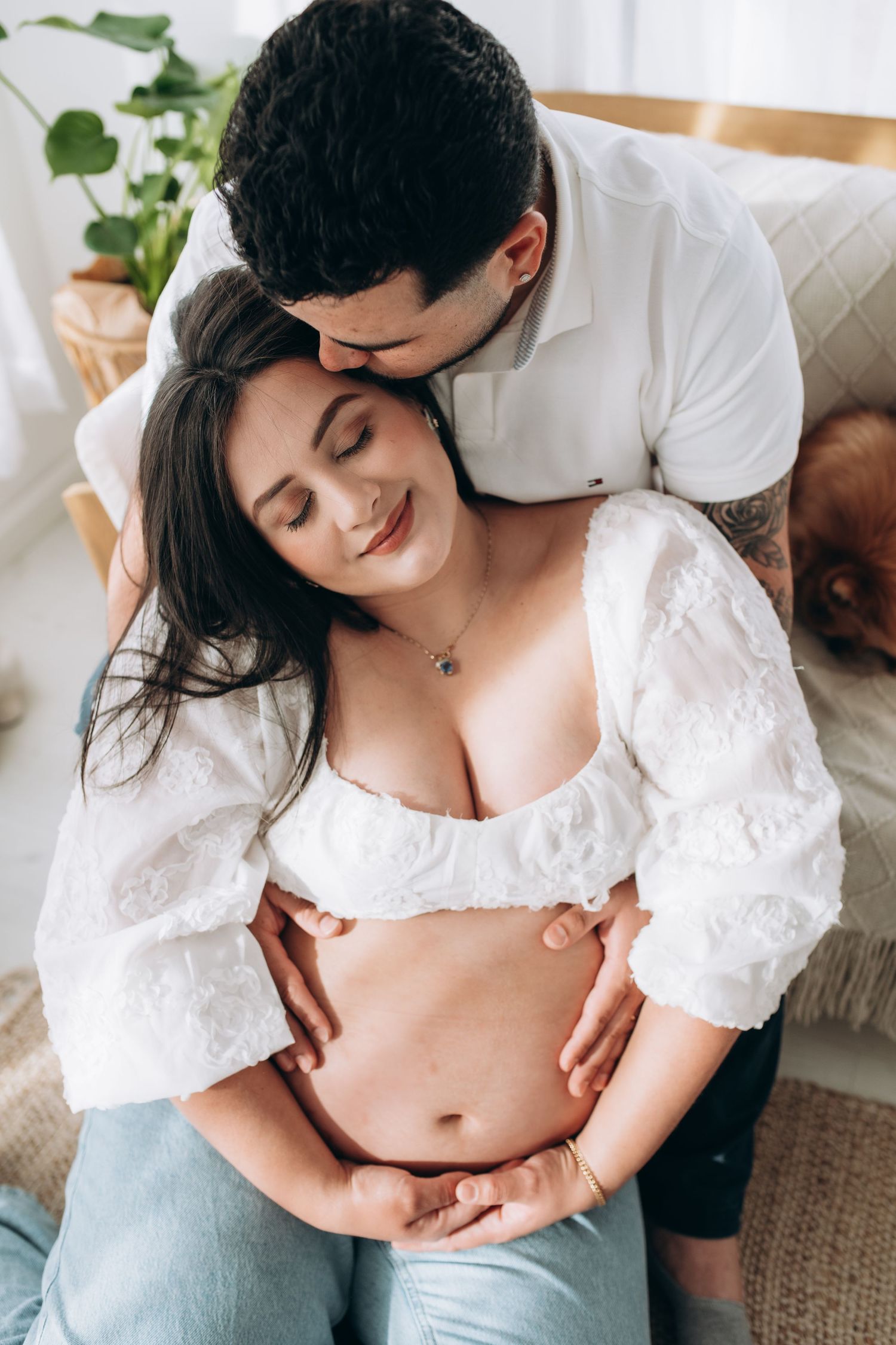 An intimate couple shares a tender moment together, with the woman wearing a white crop top and light jeans.