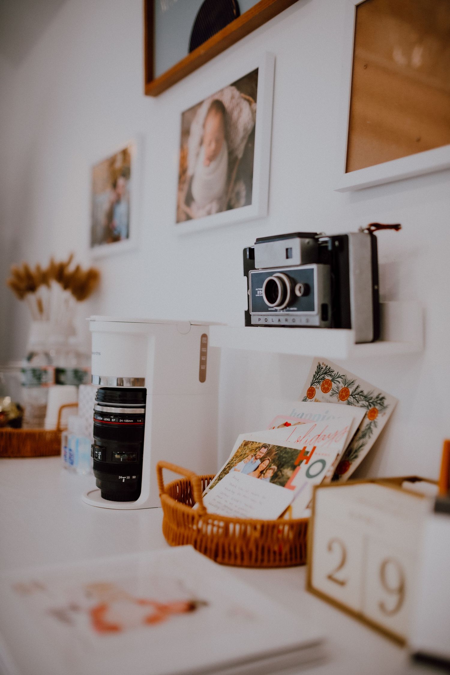 Vintage camera display with photography prints and decorative items on white shelf.