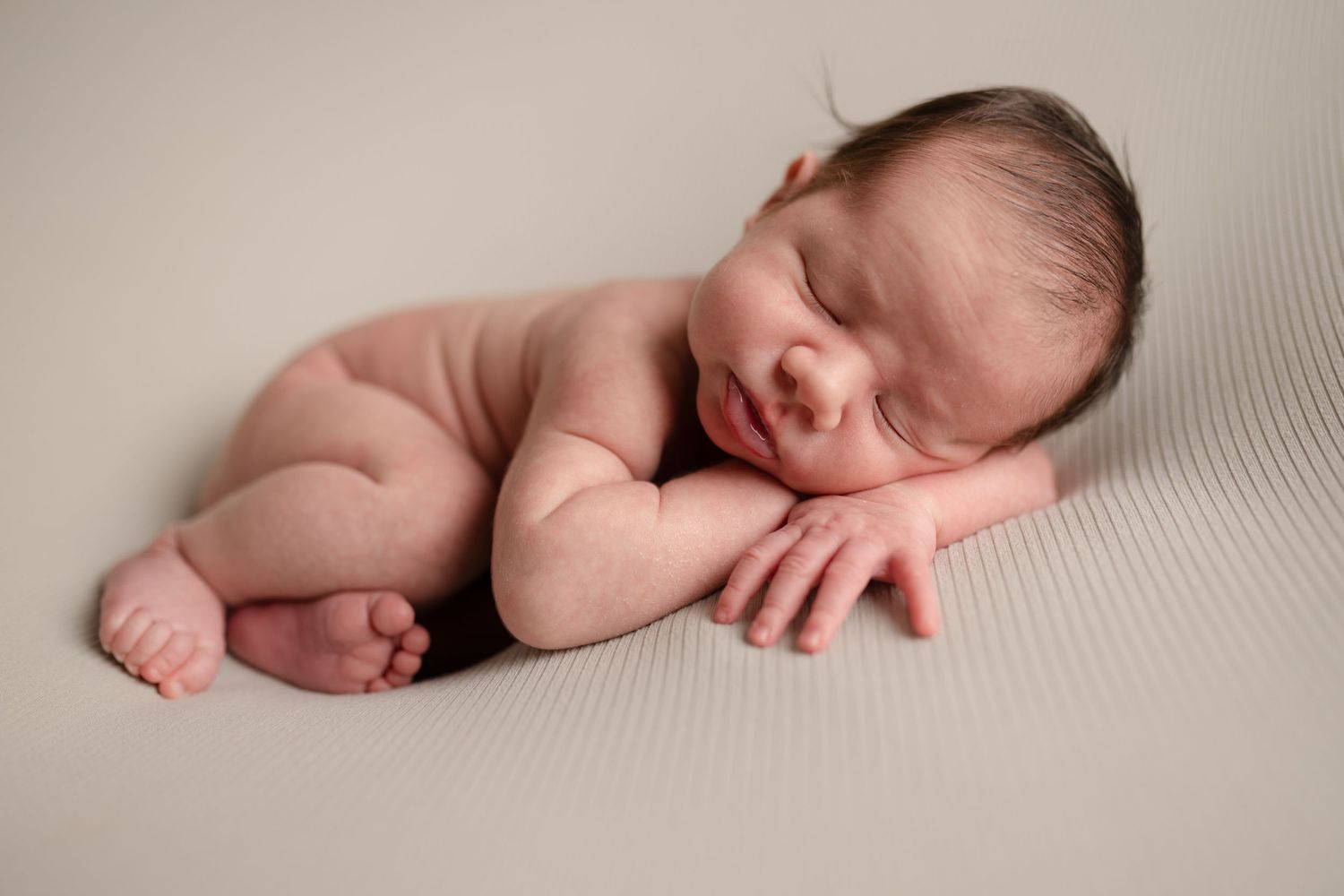 Peaceful sleeping newborn baby posed on light gray background.