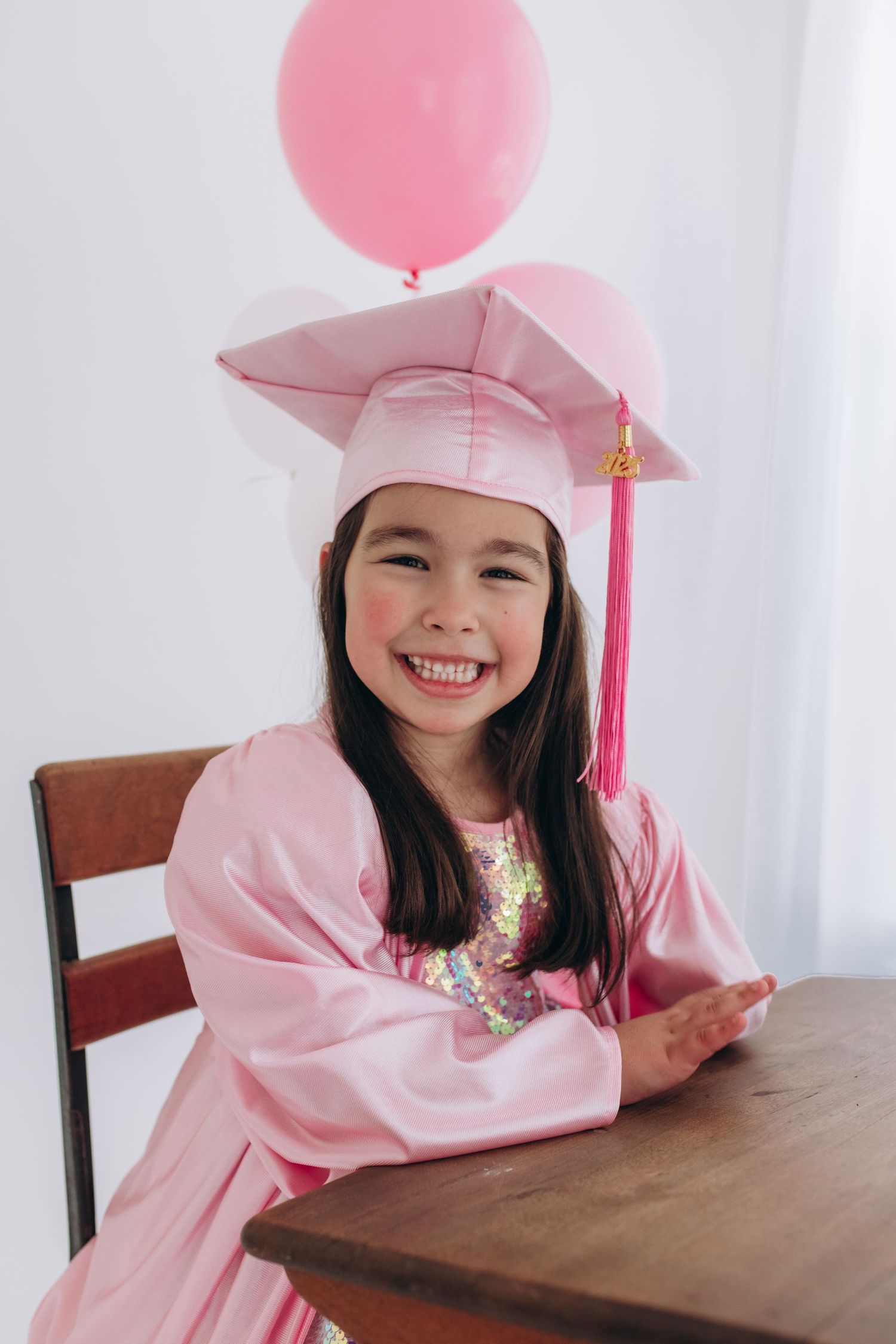 Pink graduation cap and gowns with balloons photographed in three different poses against white background.
