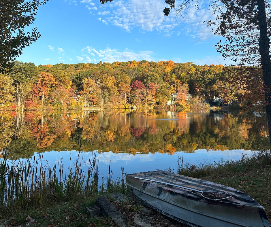 A tranquil autumn lake surrounded by vibrant fall foliage with wooden docks and calm reflective waters at sunset.