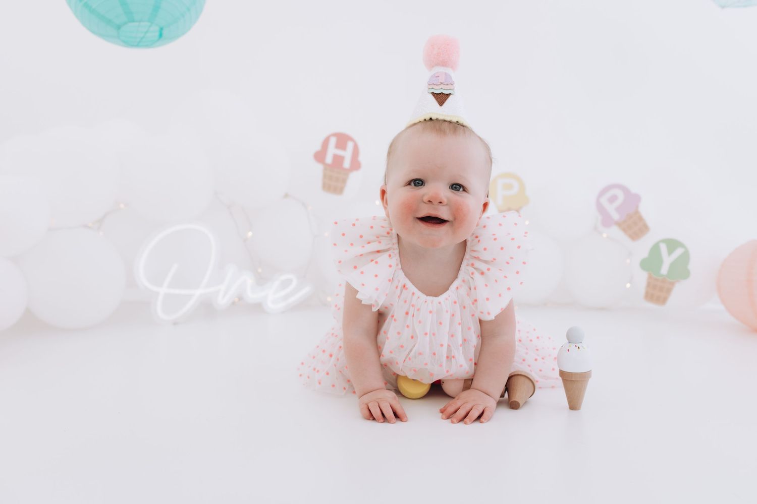 Happy baby crawling on white floor with decorative balloons and pastel accents.