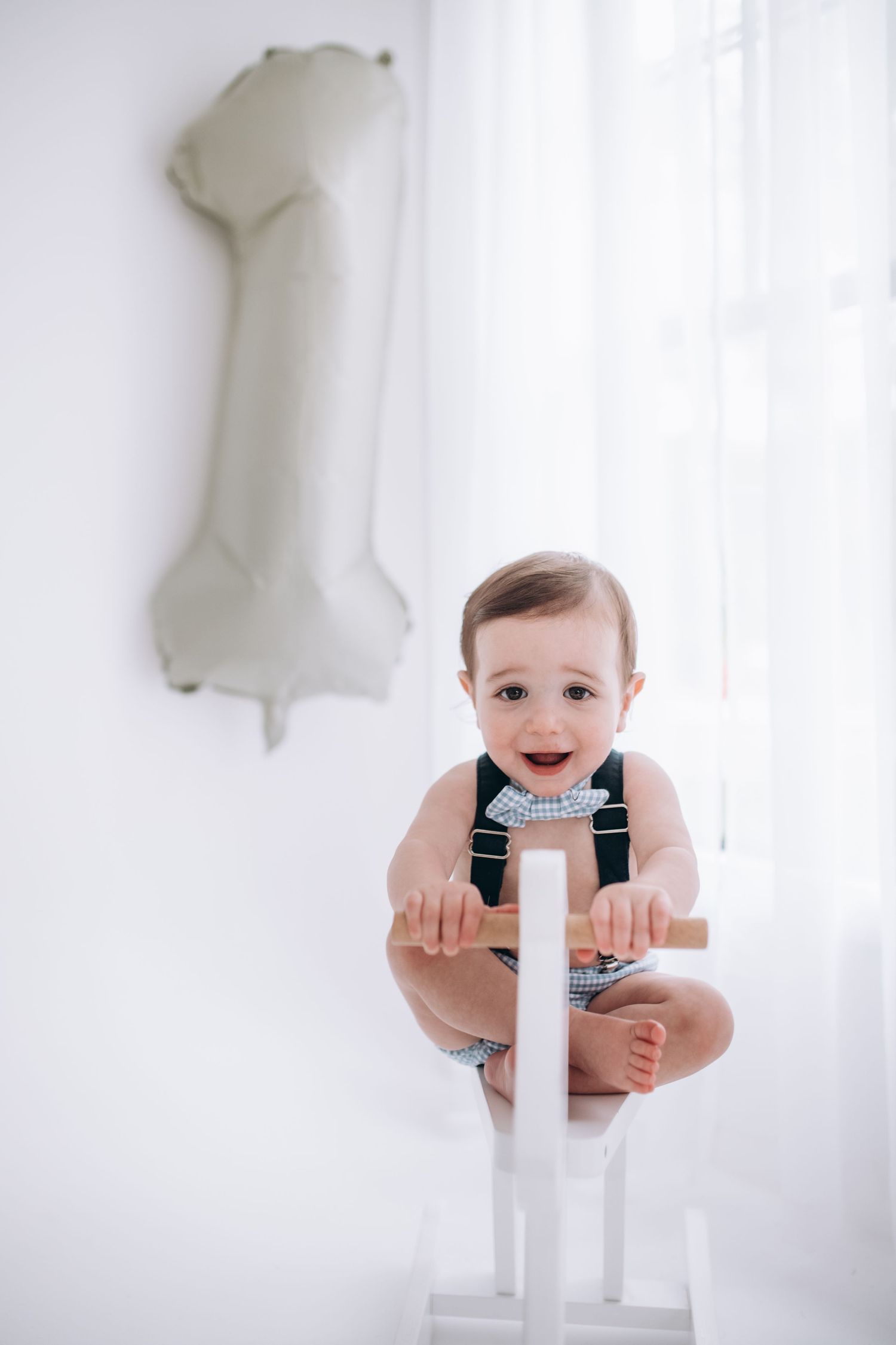 White room decorated with number one balloon and white chair for first birthday photoshoot.