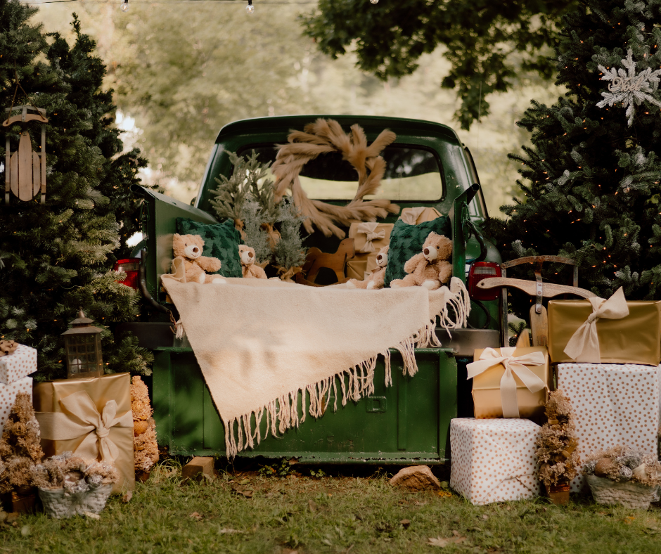 Vintage green truck decorated for Christmas with presents, blanket, and holiday decor in an outdoor setting.