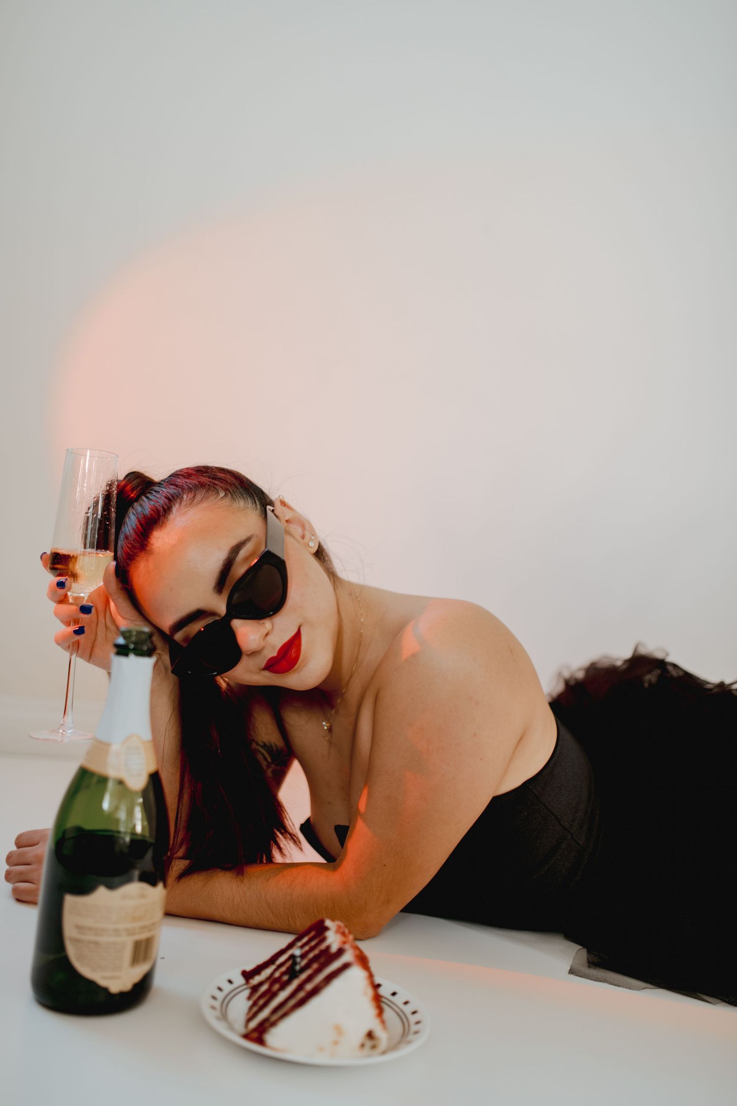 Glamorous portrait of woman in sunglasses with champagne and cake.