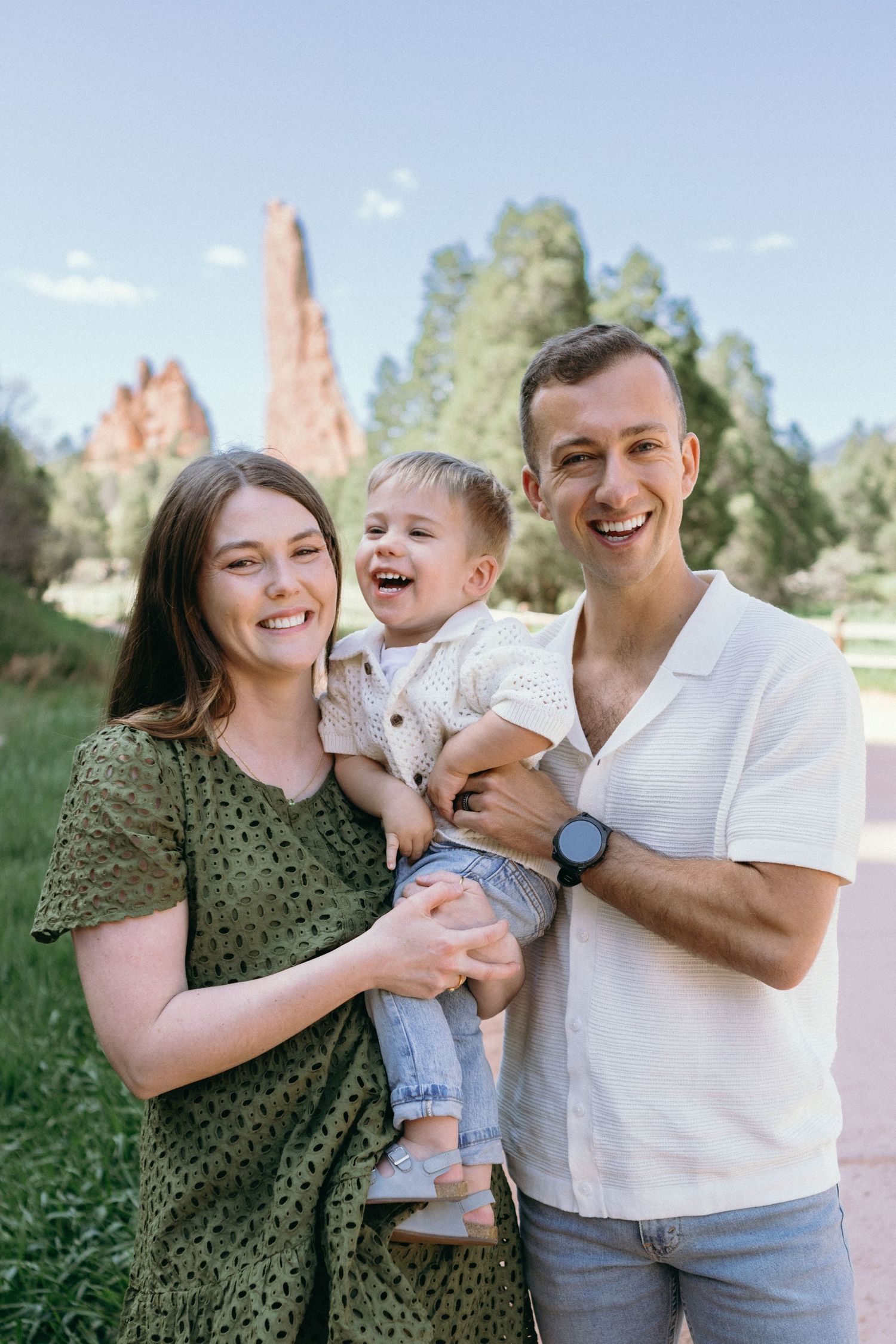 Family enjoying playful moments together outdoors on a sunny day in a grassy field.