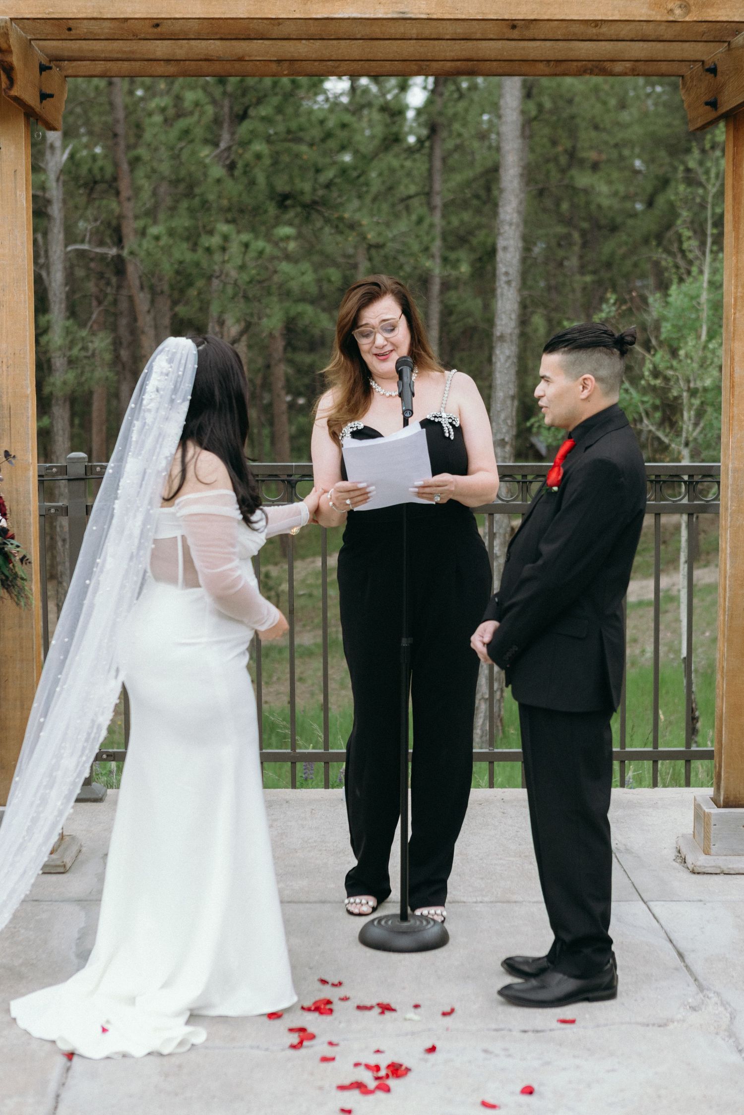 A sequence of four candid wedding photos showing playful moments between a bride and groom under a wooden gazebo outdoors.