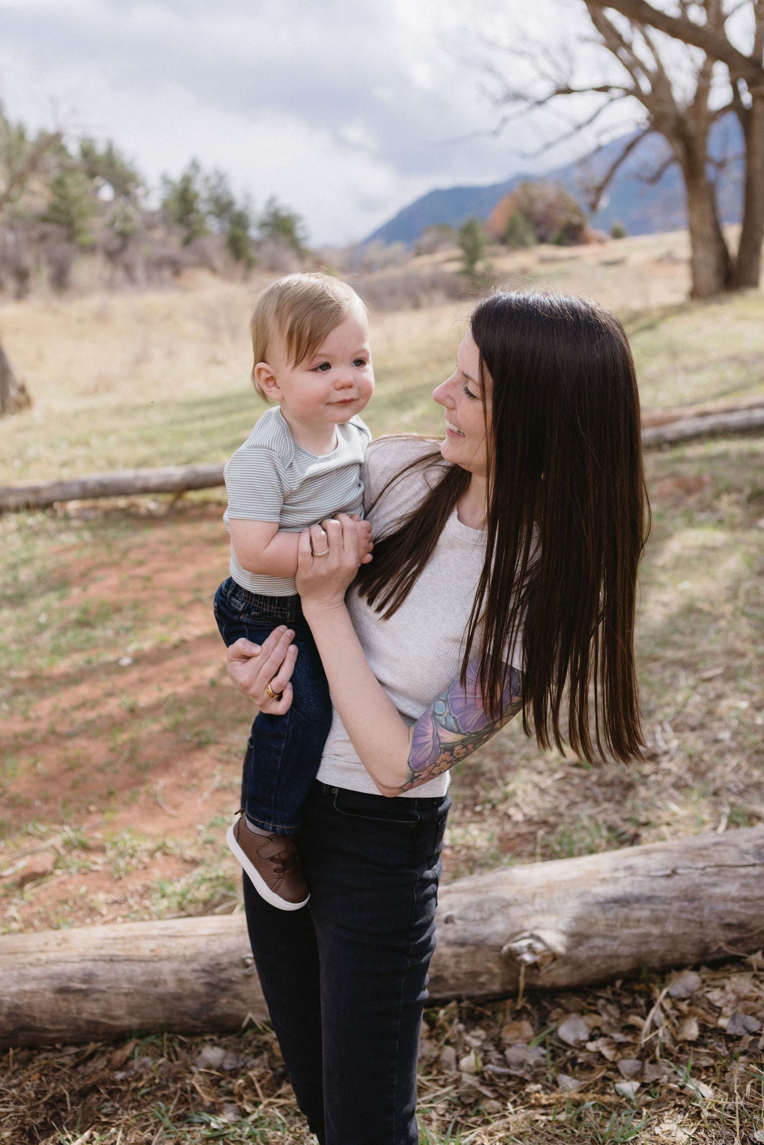 Outdoor portrait of a mother and child sharing a joyful moment together in a natural mountain setting.