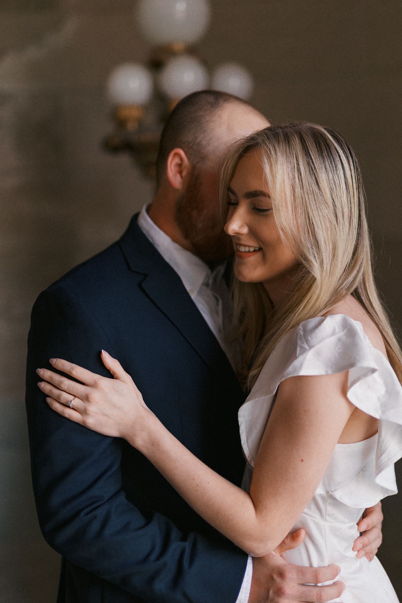 Elegant couple in formal attire sharing an intimate moment indoors.