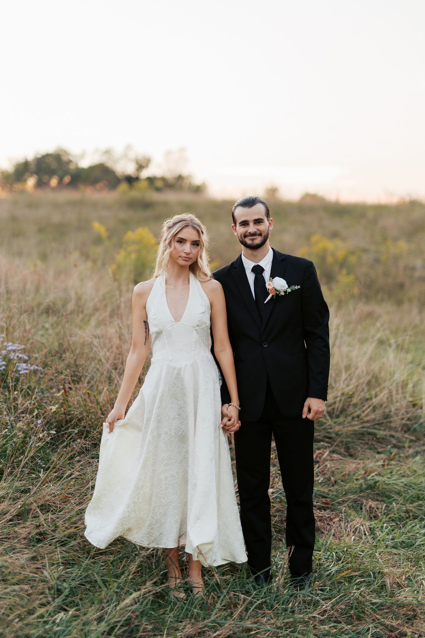 A couple poses together in a golden field during their wedding photoshoot.
