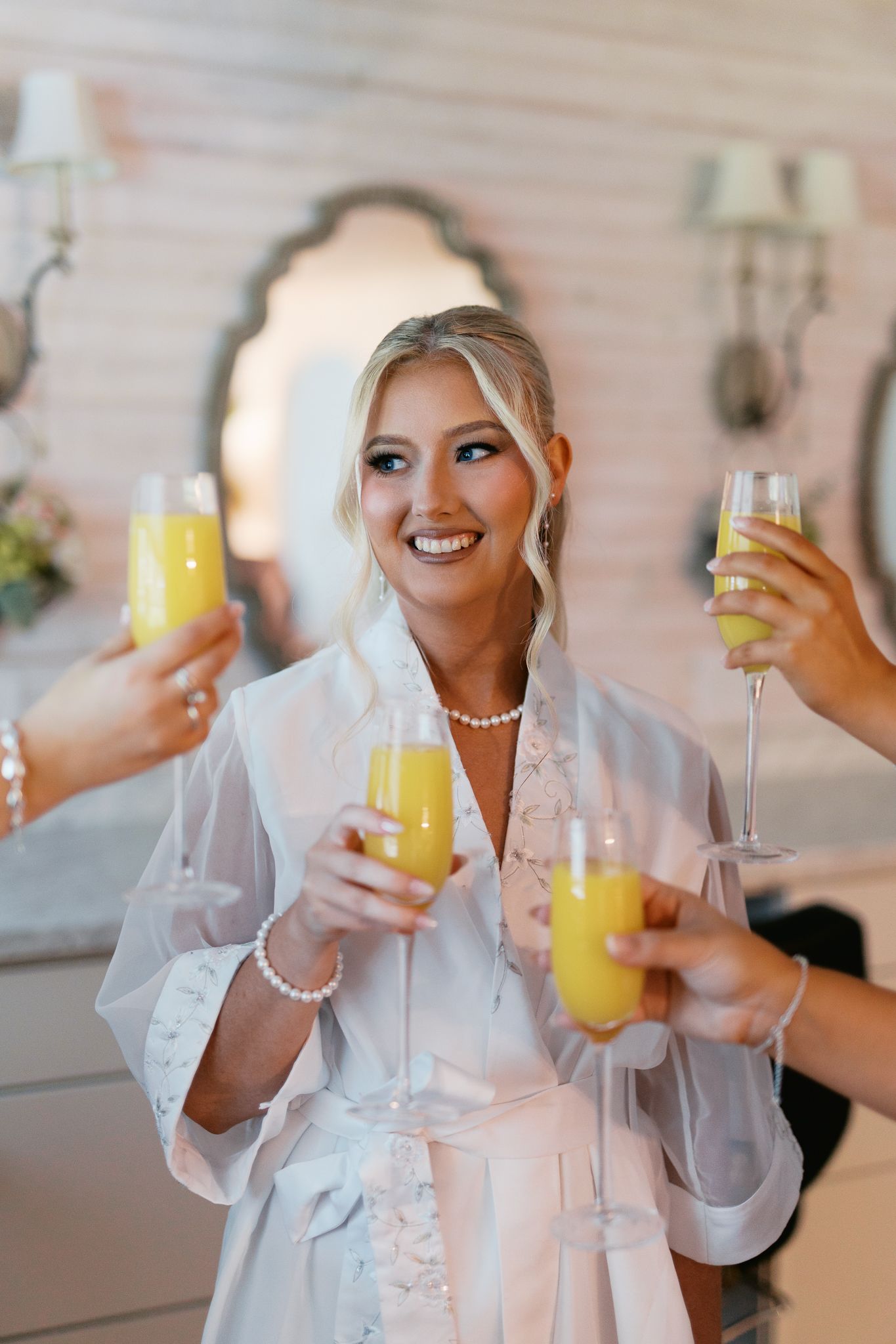 People toasting with mimosas and champagne during wedding preparations.