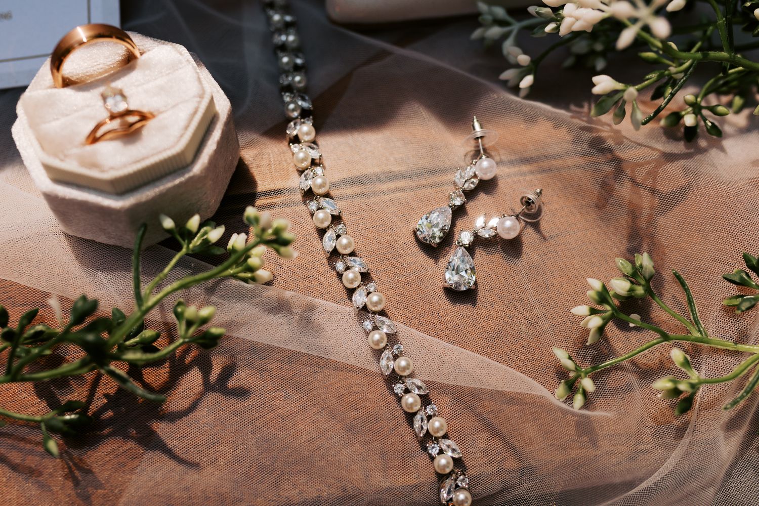 Wedding detail shot of crystal beads and greenery decorations on a rustic wooden surface.