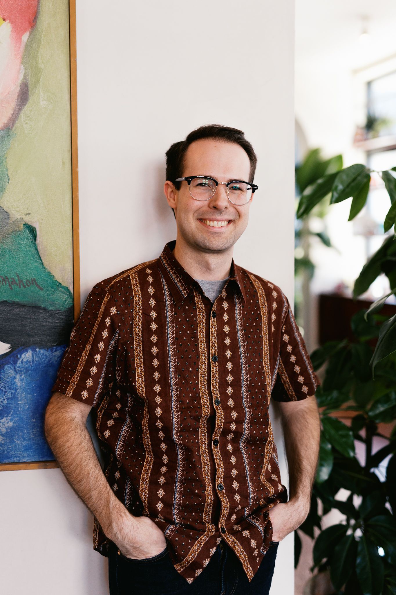Samuel Stallard wearing vintage brown striped shirt posing against abstract wall art.