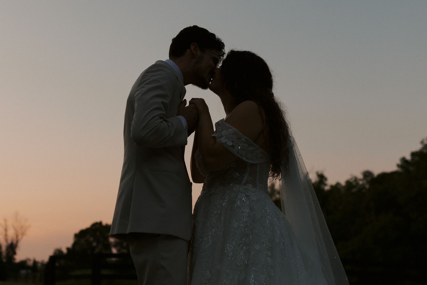Silhouettes of a couple embracing during sunset on their wedding day.