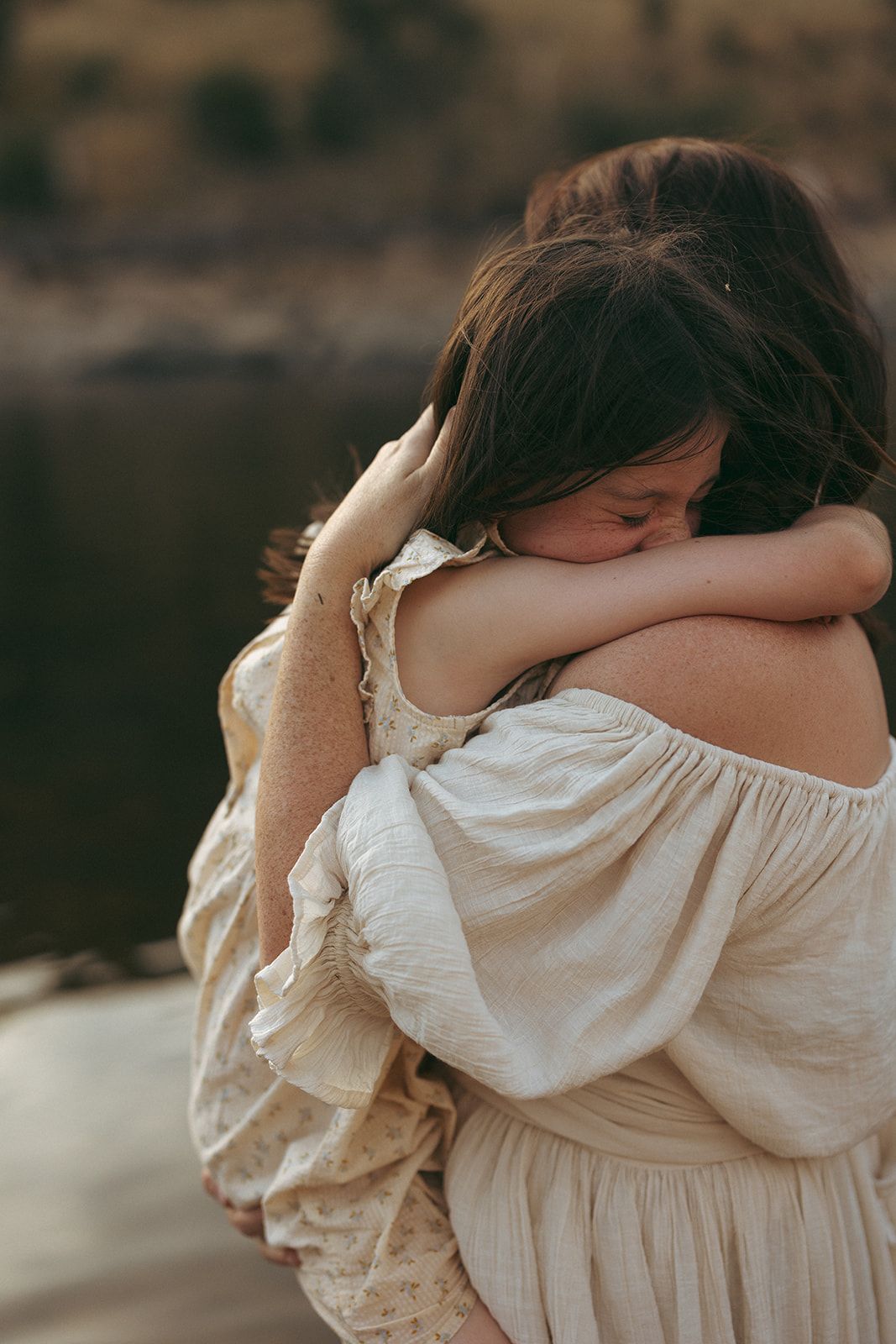 Two people sharing an intimate embrace in white clothing by a lake. Neurodivergent family