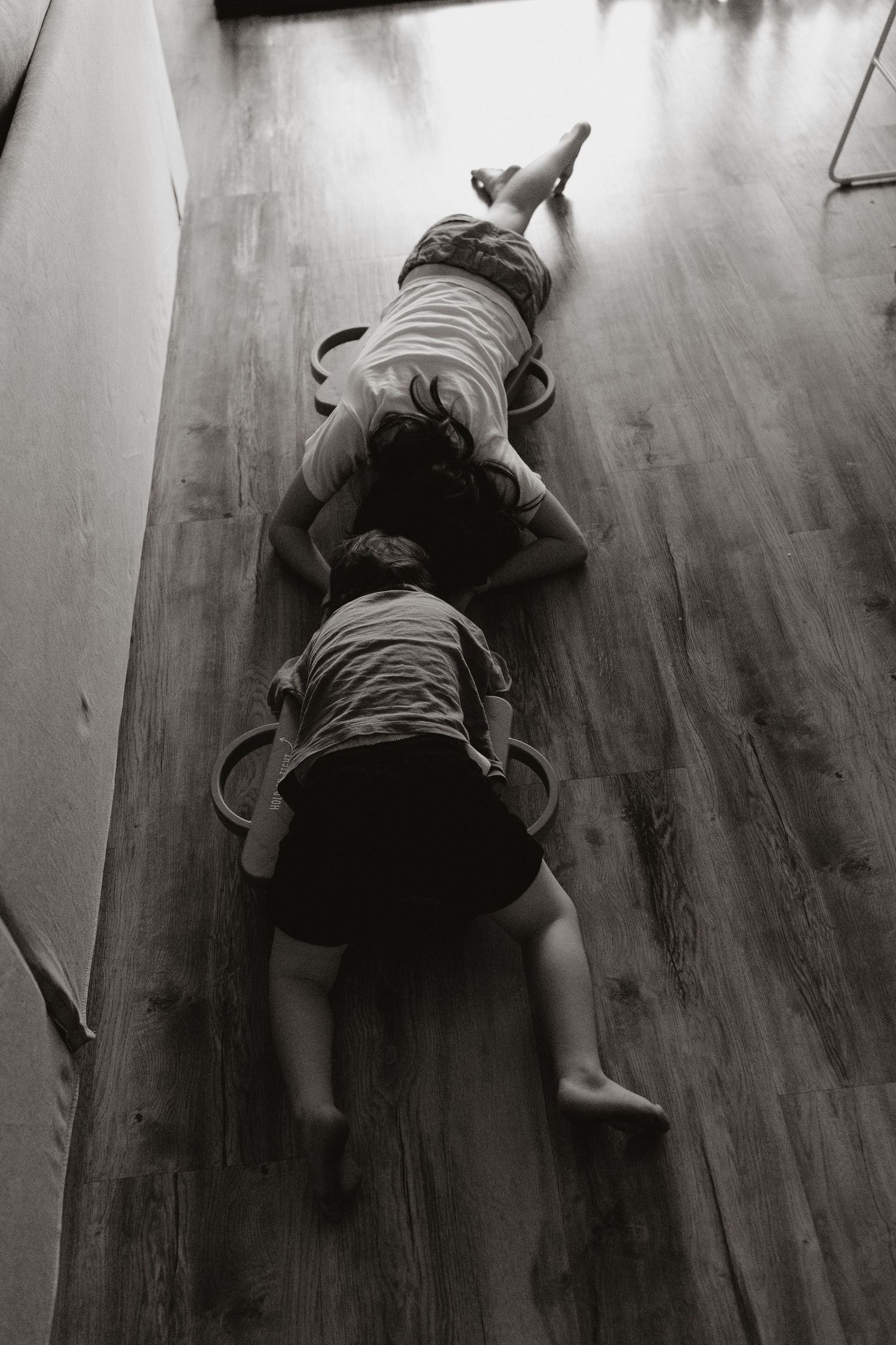 Two children lying on wooden floor seen from above in black and white. Children with Autism