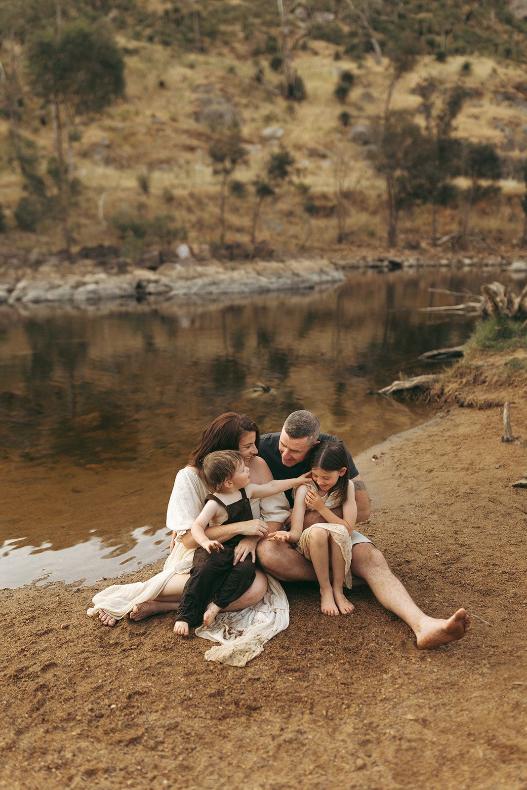 Family spending quality time together by a serene lake with rocky shoreline. Neurodivergent family