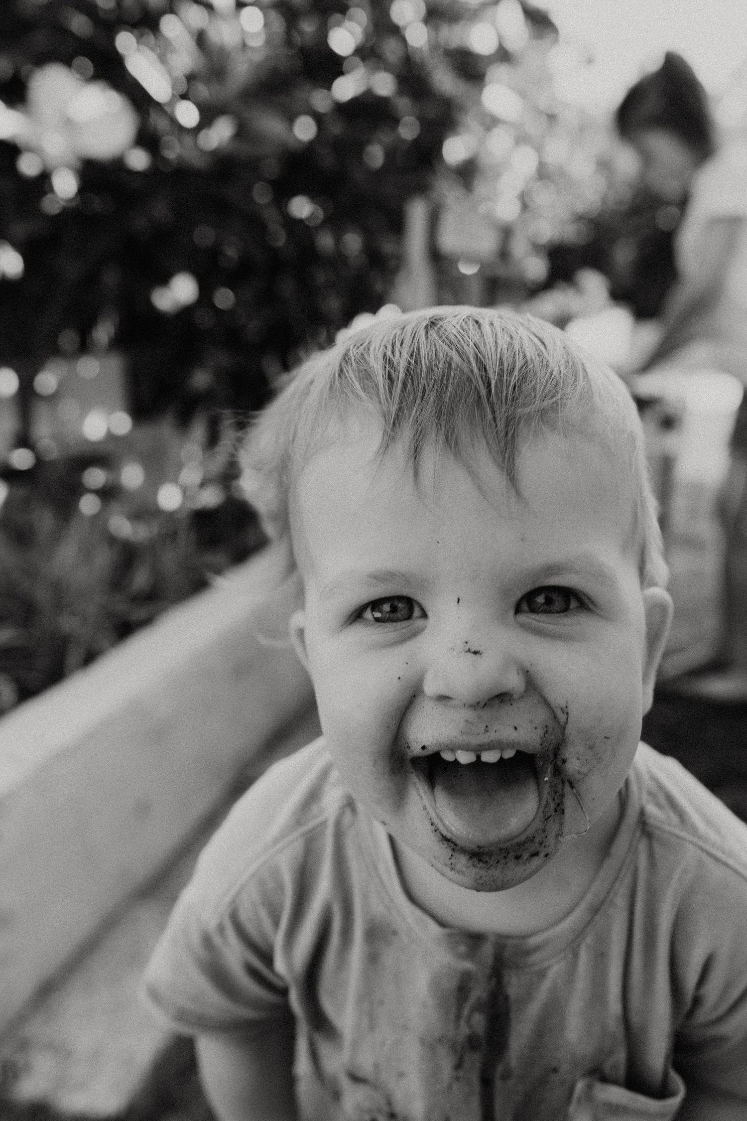 Black and white close-up portrait capturing pure joy and laughter with a messy face. Child with Autism