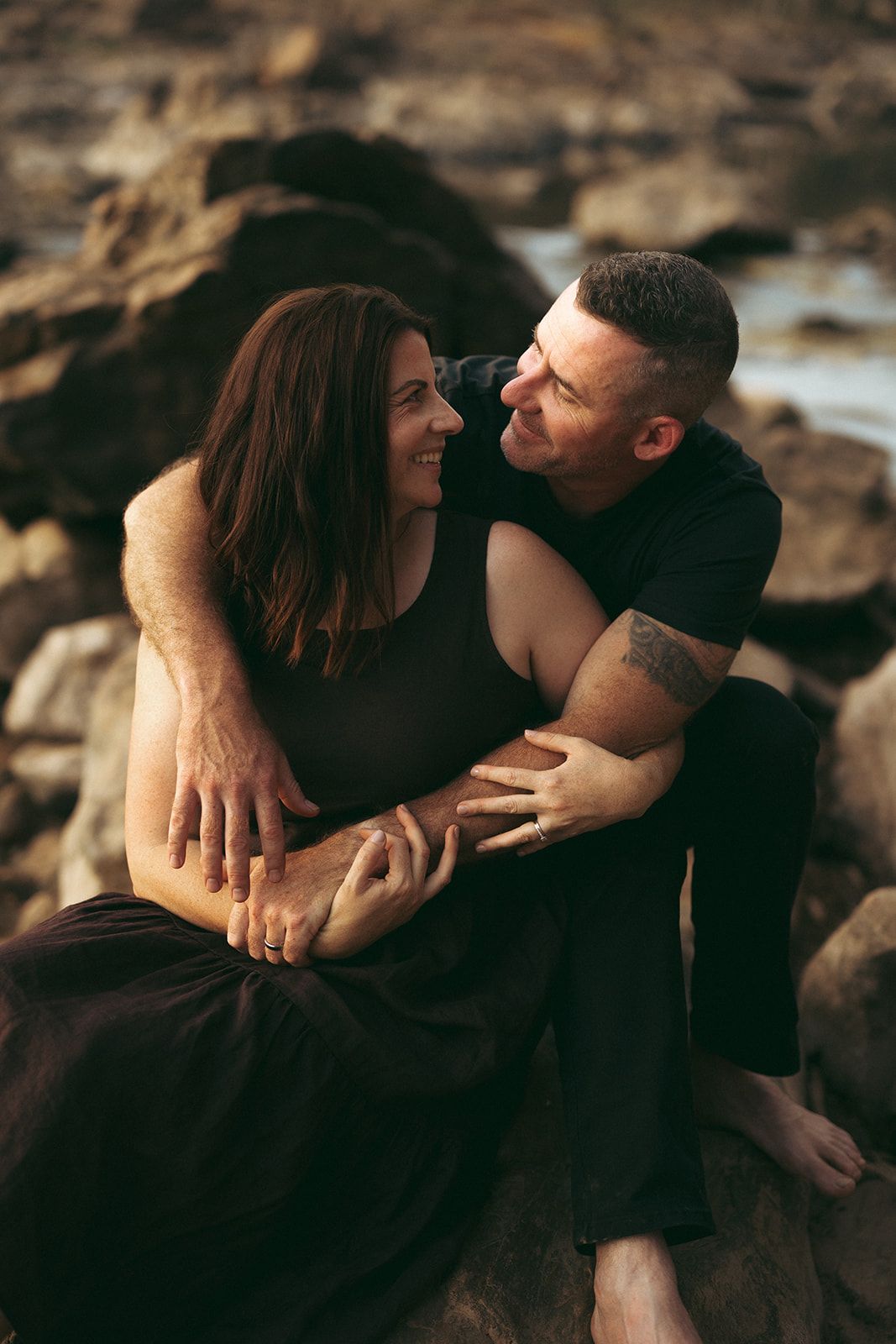 Couple sharing intimate moment while sitting on coastal rocks at sunset. Courtney Healy Photography Yanchep Perth