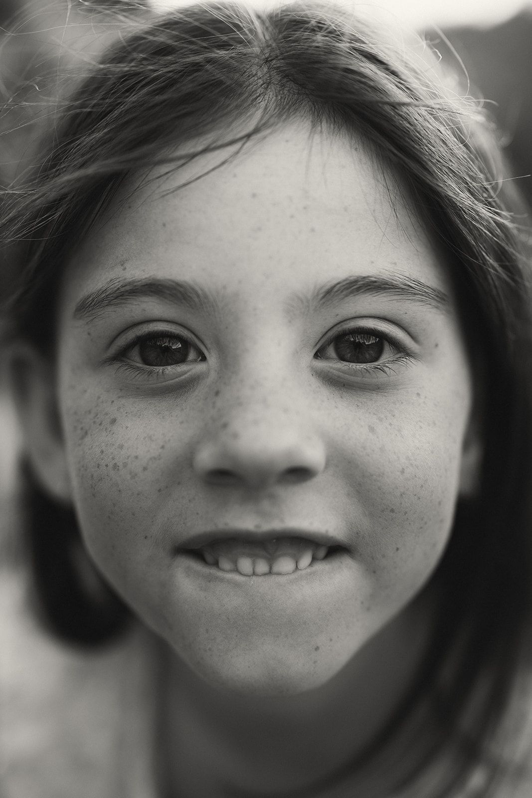 Black and white portrait showing natural freckles and genuine smile.