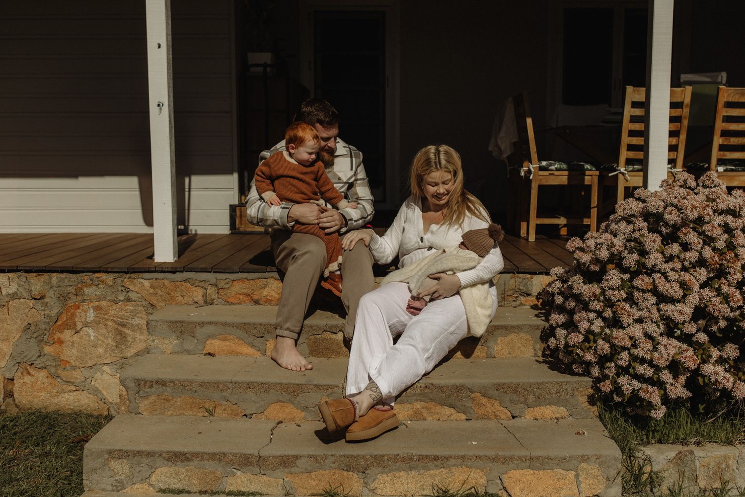 People enjoying time together on outdoor stairs while relaxing with beverages and books.