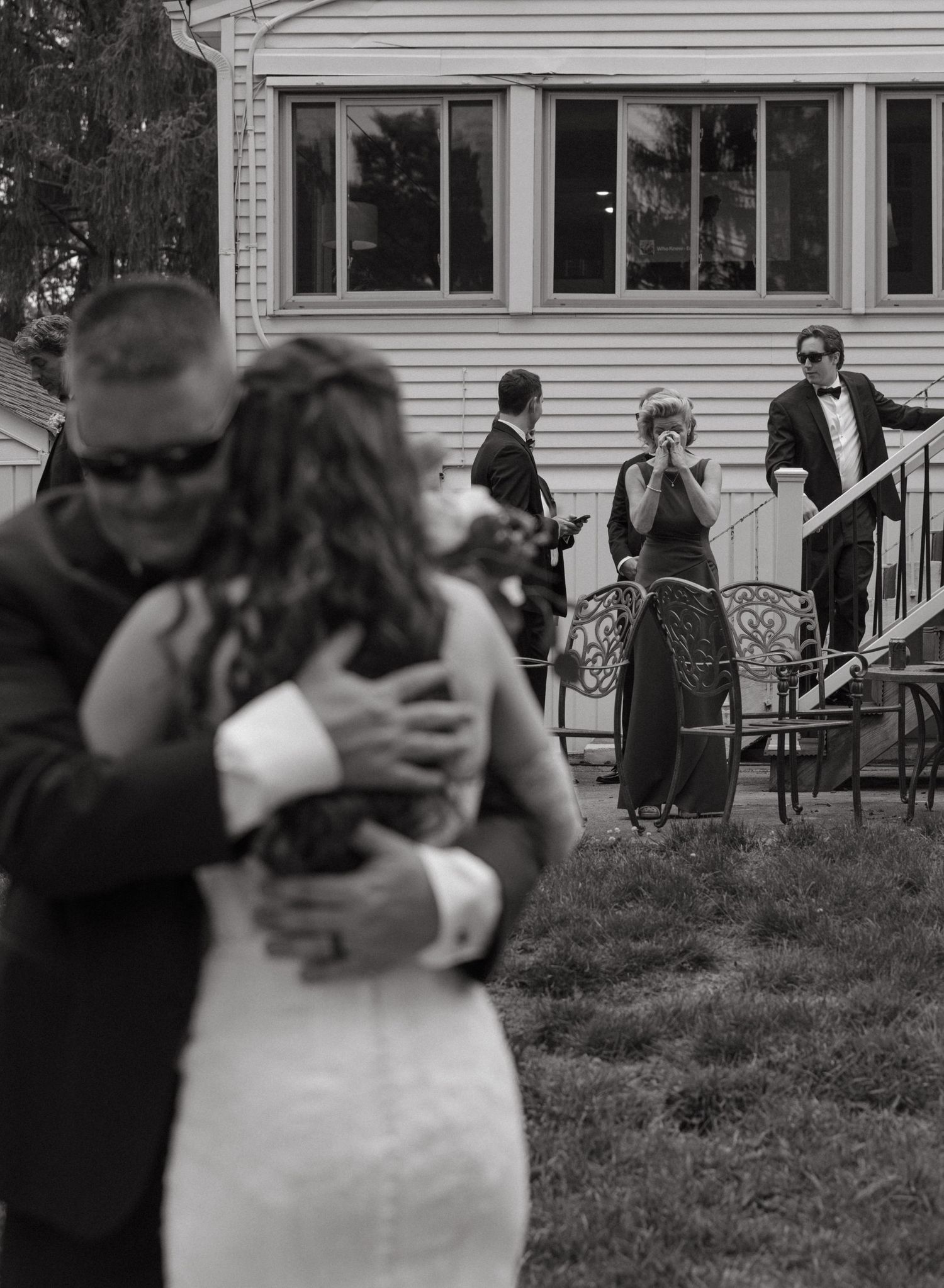 Emotional black and white photo of mom watching dad and daughter first look. Documentary photography