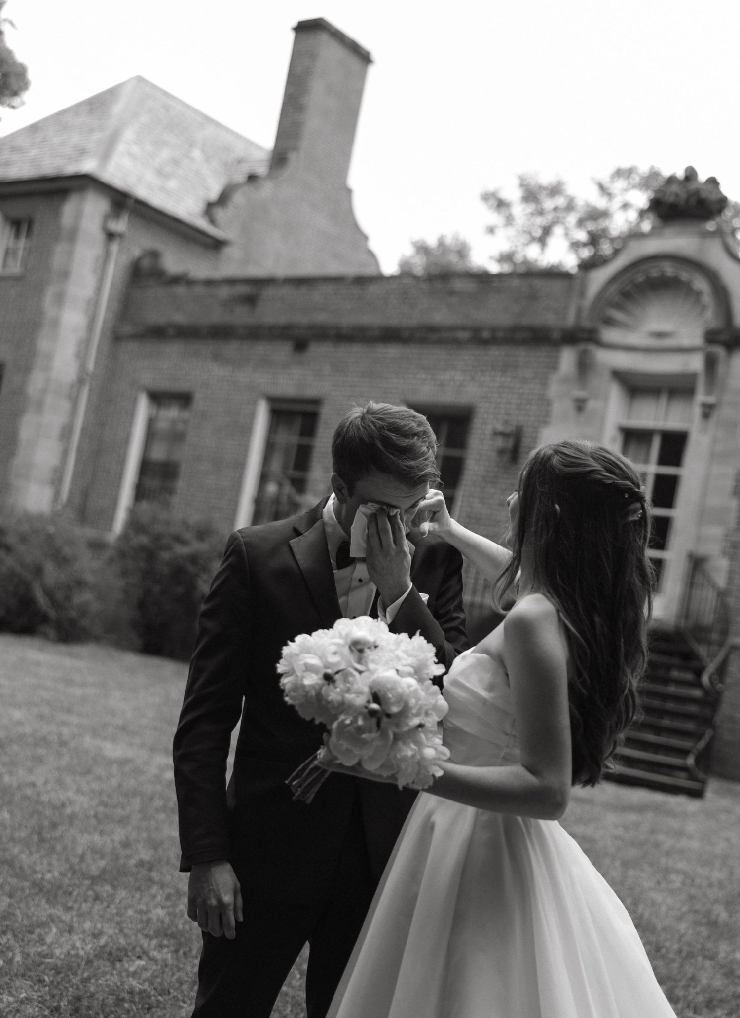 Emotional groom black and white photo first look at an estate before wedding ceremony.