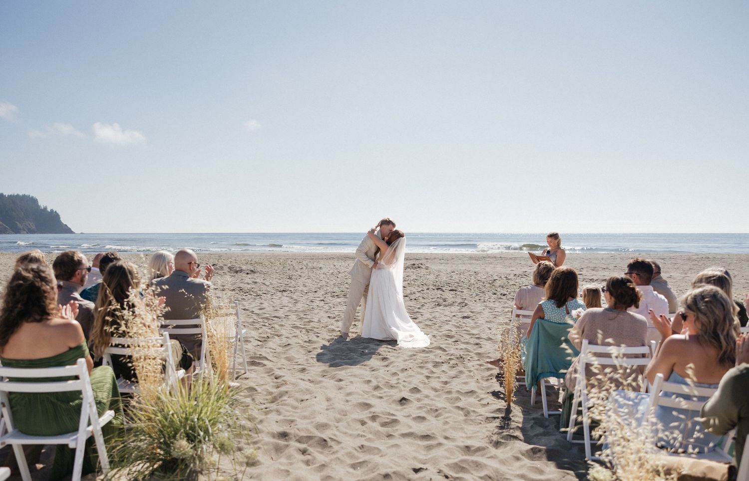 Beach wedding ceremony setup with guests seated overlooking the ocean.
