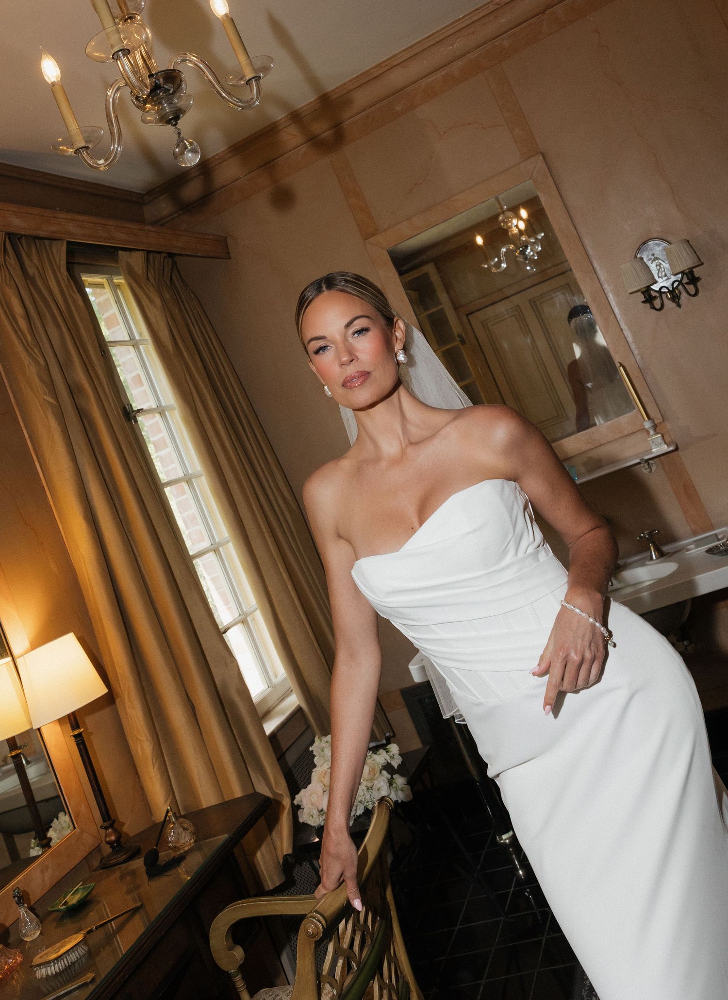 Editorial flash bridal portrait in elegant room with warm lighting and chandelier.