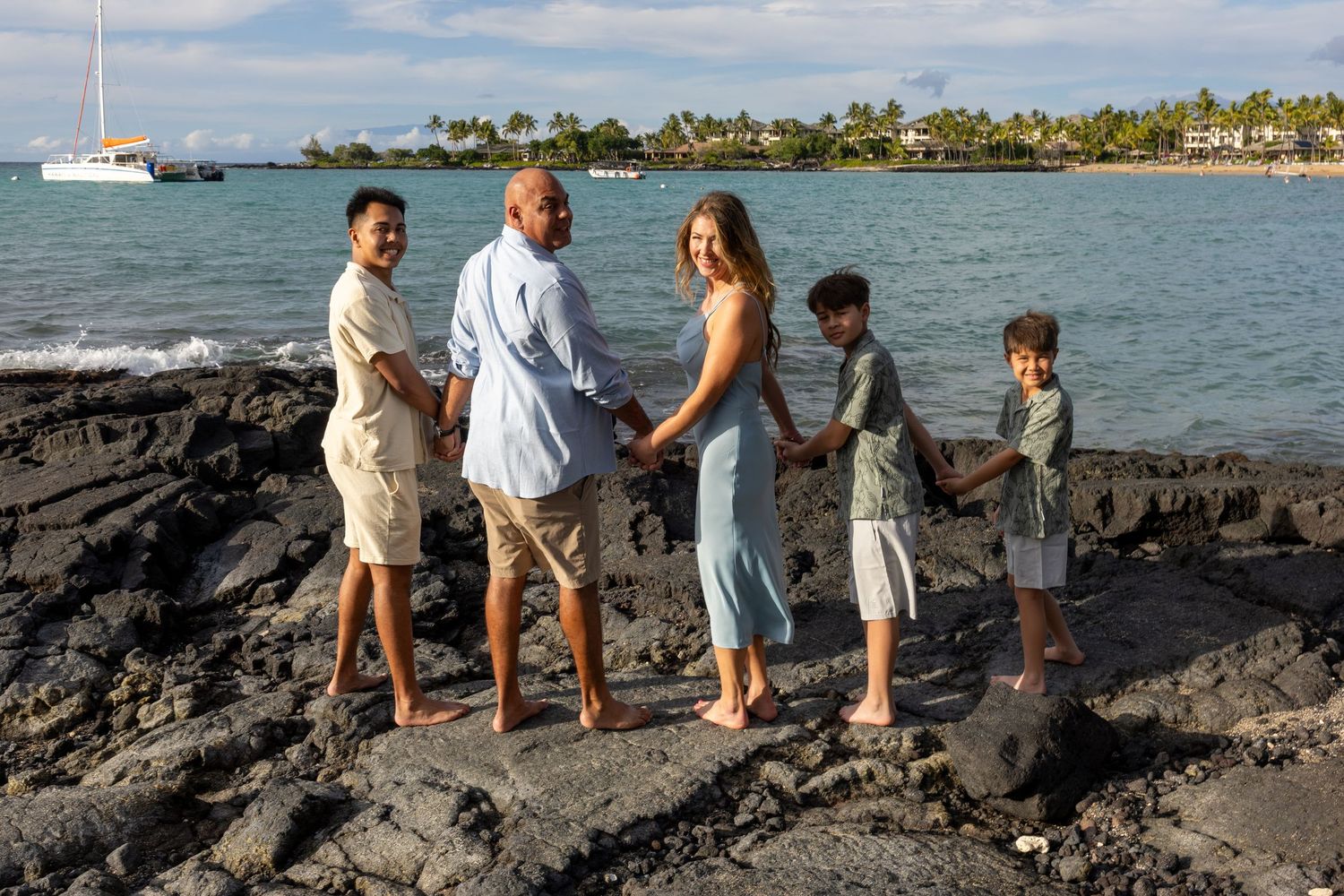 Our Kona family photographer captures a family on lava rock looking back at the photographer at Anaehoomalu Bay. *