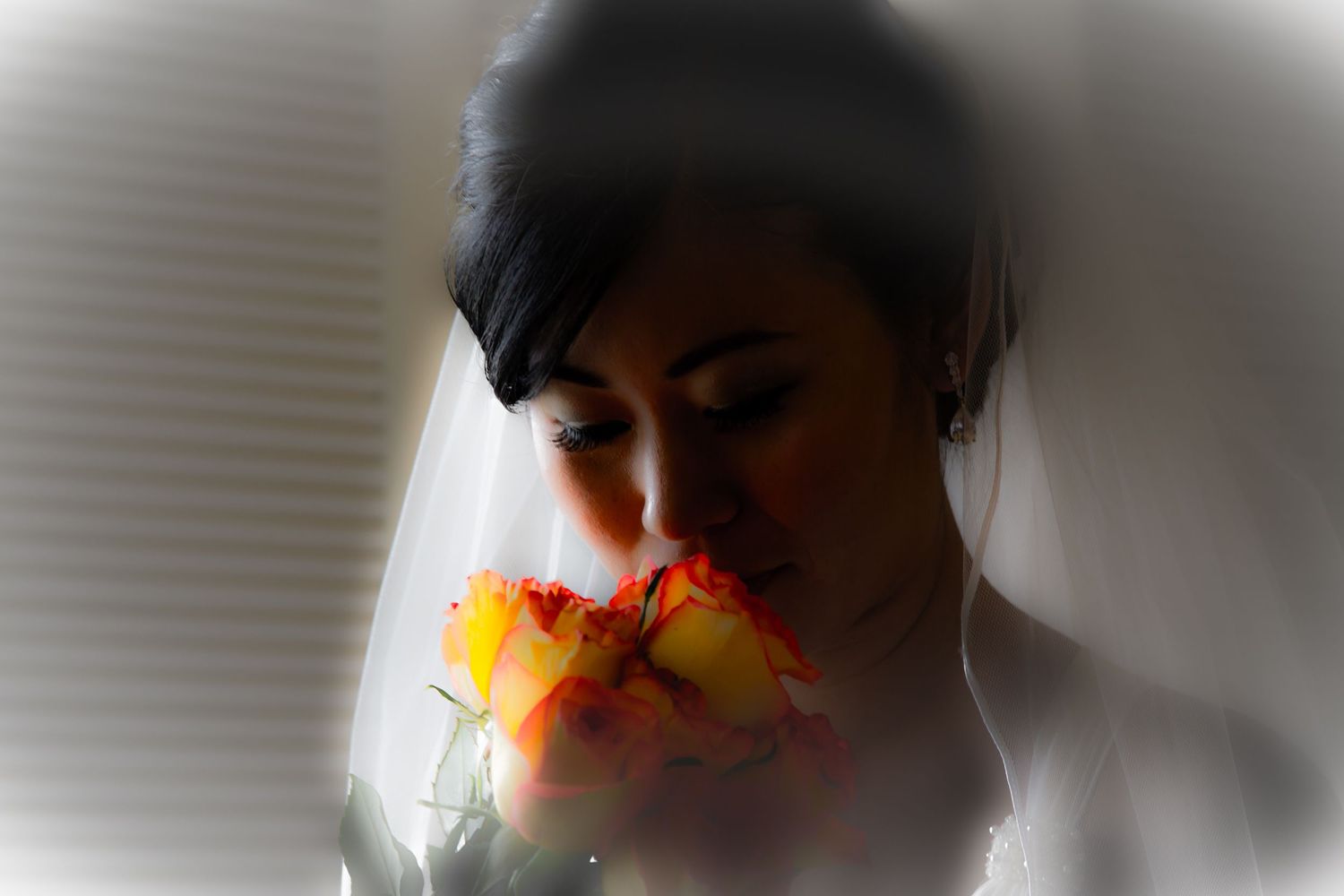 Artistic close-up portrait of bride smelling orange flower with soft focus effects.