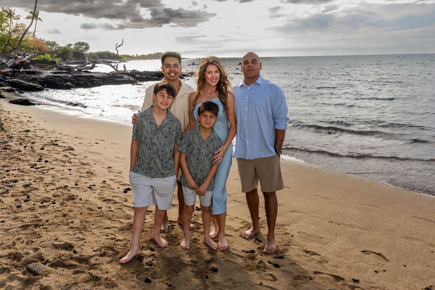A family with pre-teen children and a teenage son poses at Anaehoomalu Bay, captured by a Big Island family photographer. *
