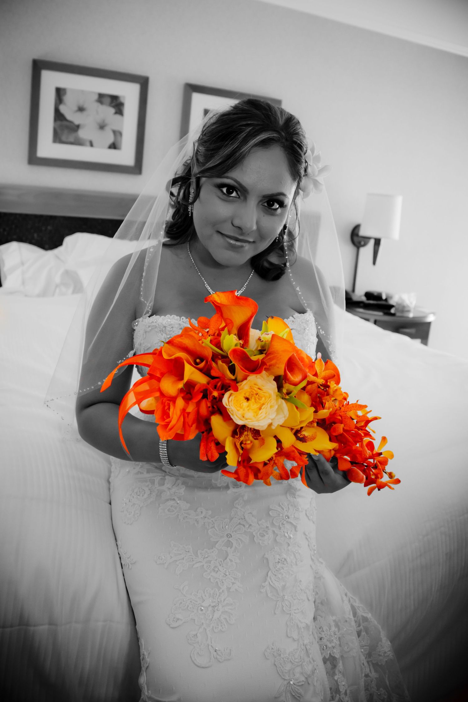 At the Moana Surfrider of Waikiki a selective color photo highlights vibrant orange bouquet against black and white bridal portrait.