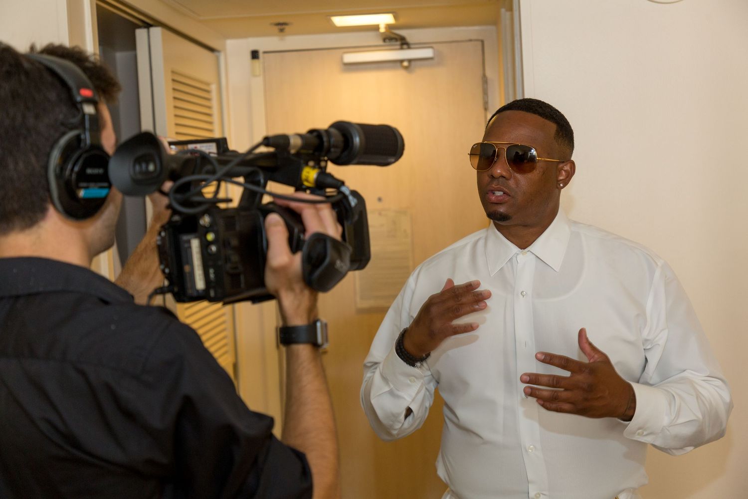Man in white shirt being interviewed on camera in an indoor setting.