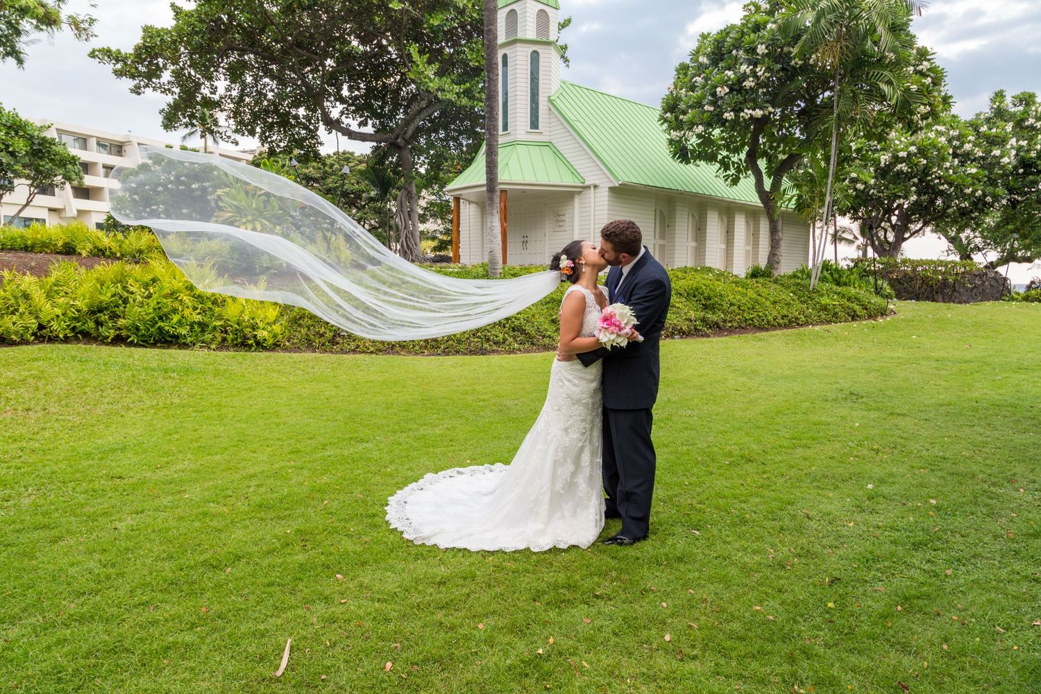 A bride and groom embrace on the lawn of the Bayside Wedding Chapel of the Outrigger Kona Resort & Spa in Kailua Kona, Hawaii.