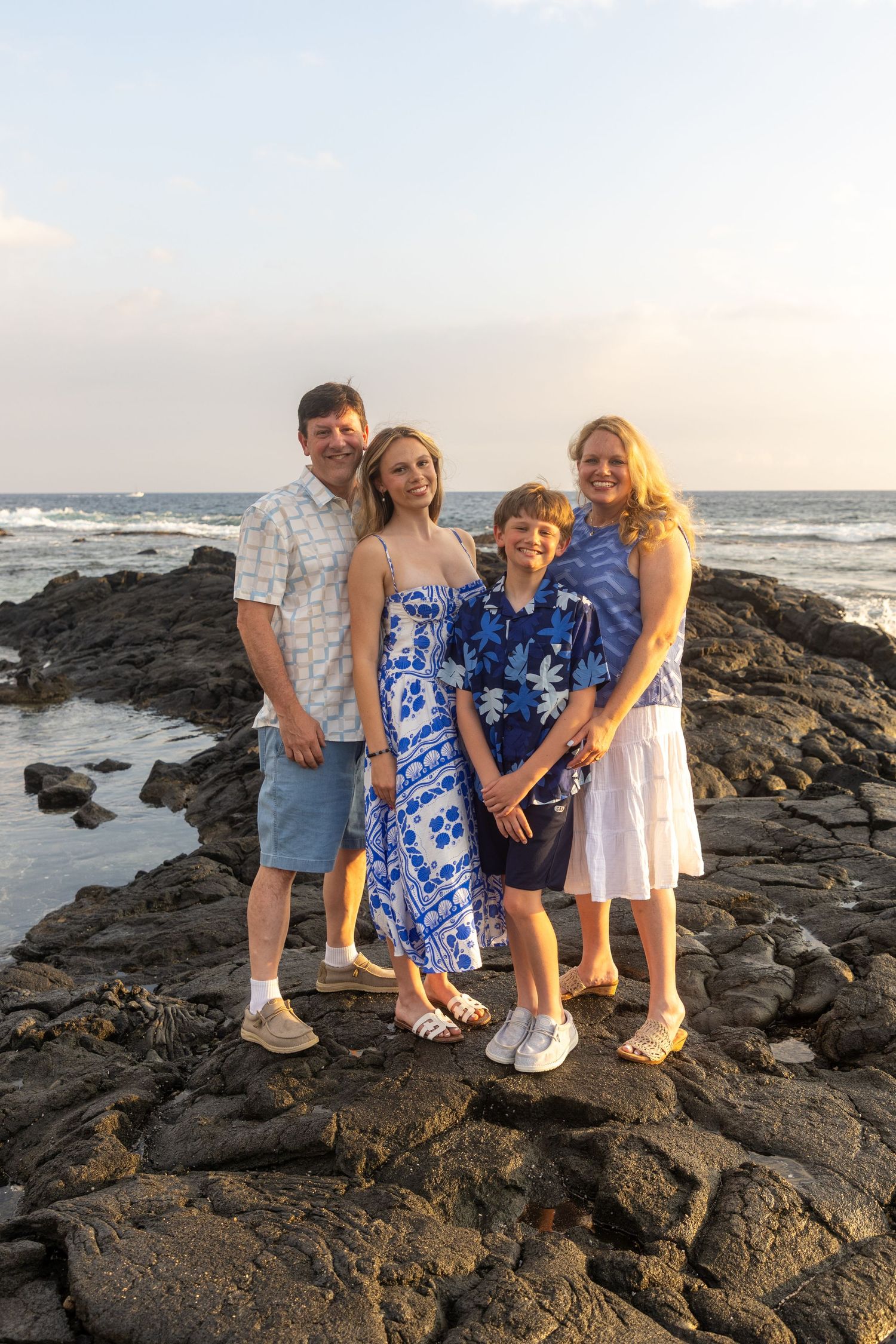 Family portrait of parents and kids on ocean lava rocks at Old Airport Beach, captured by a Big Island family photographer. *