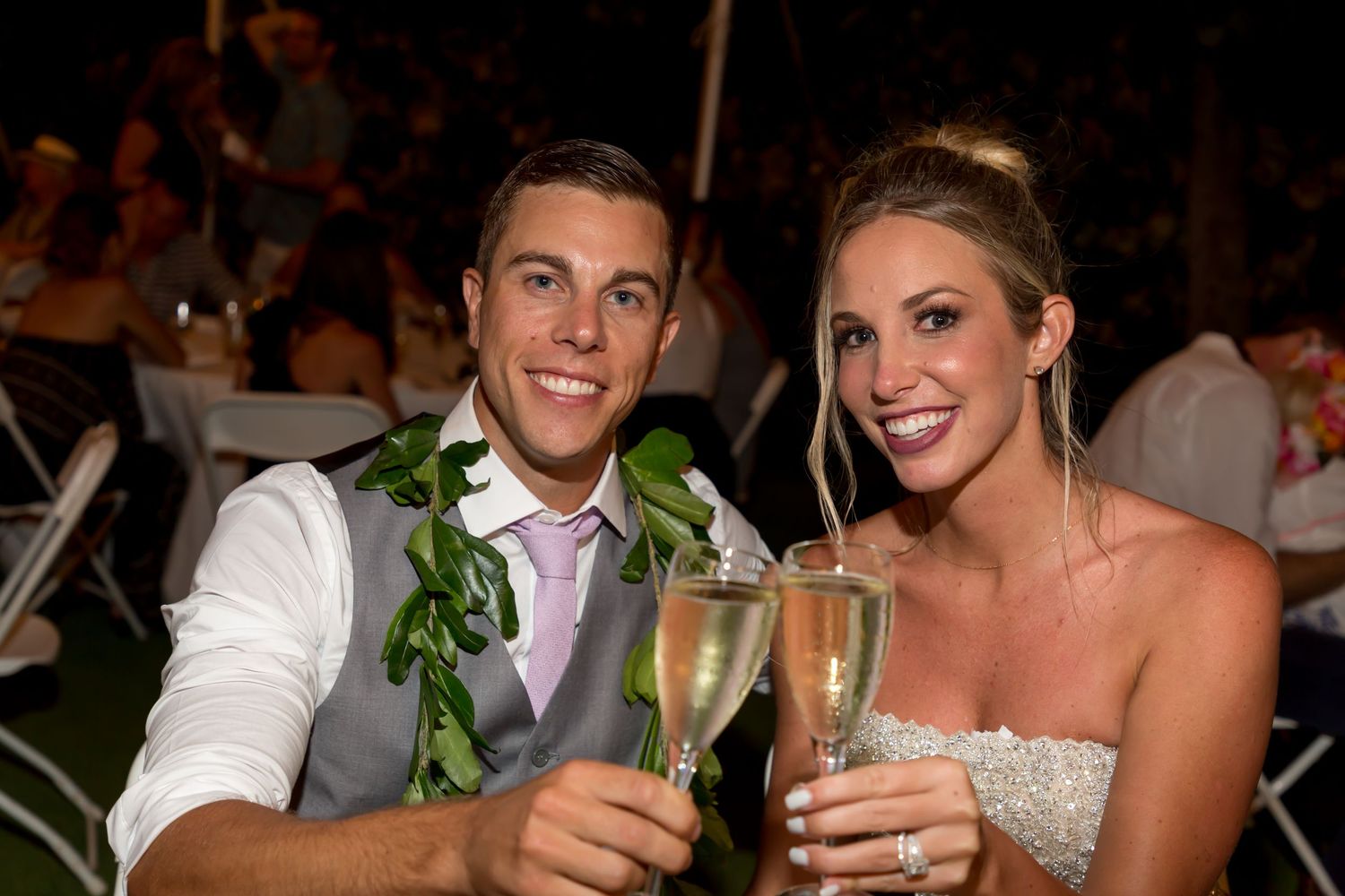 Bride and groom toasting with champagne glasses at outdoor wedding reception, smiling couple in formal attire.