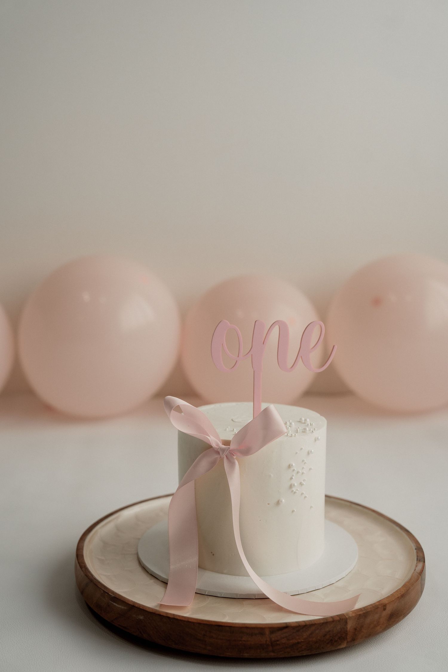 Minimalist Easter decor with pink eggs and white ceramic decorations arranged on wooden plates in a soft pastel setting.