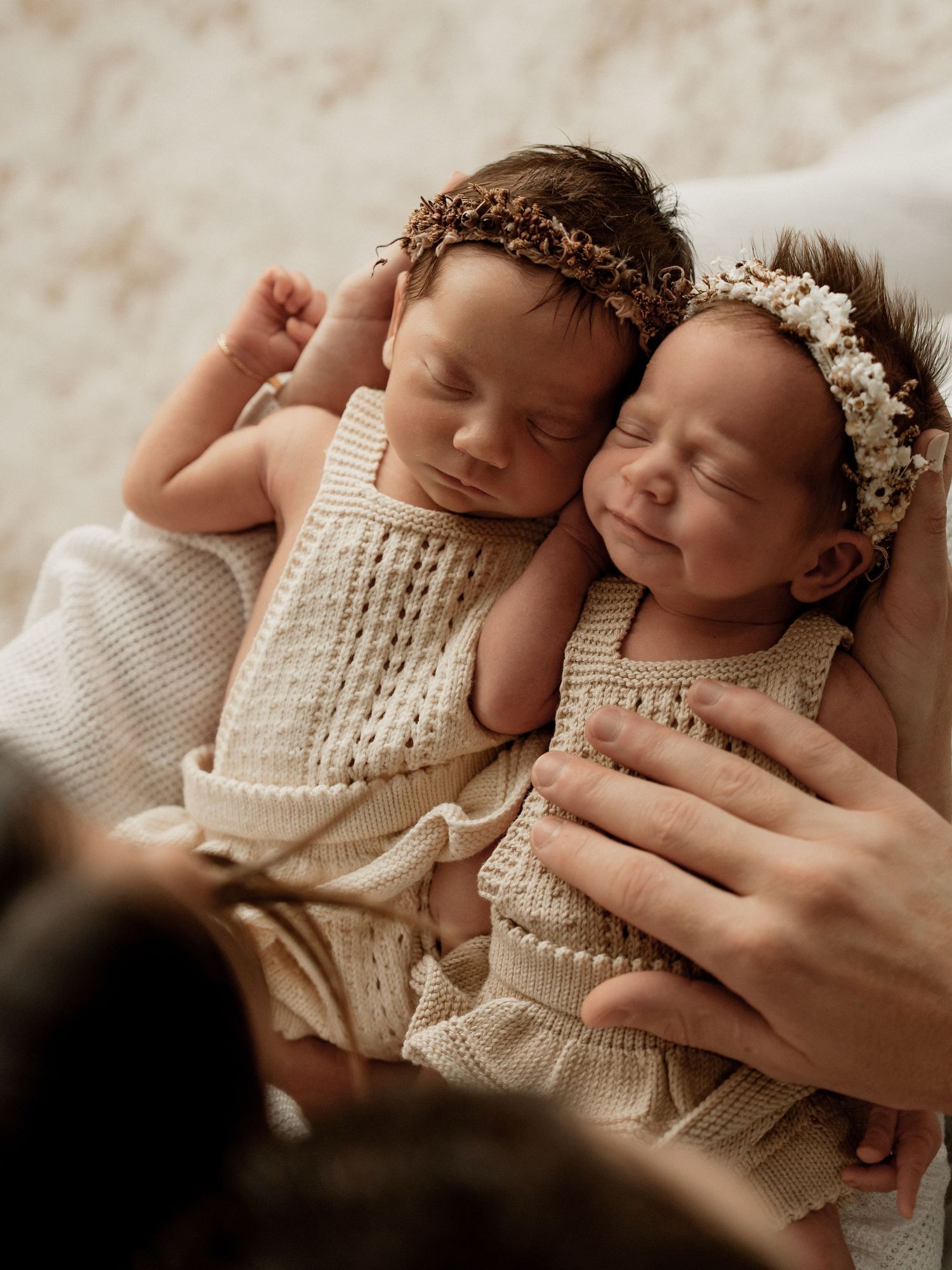 Newborn baby wearing knit sweater rests peacefully during professional photography session.