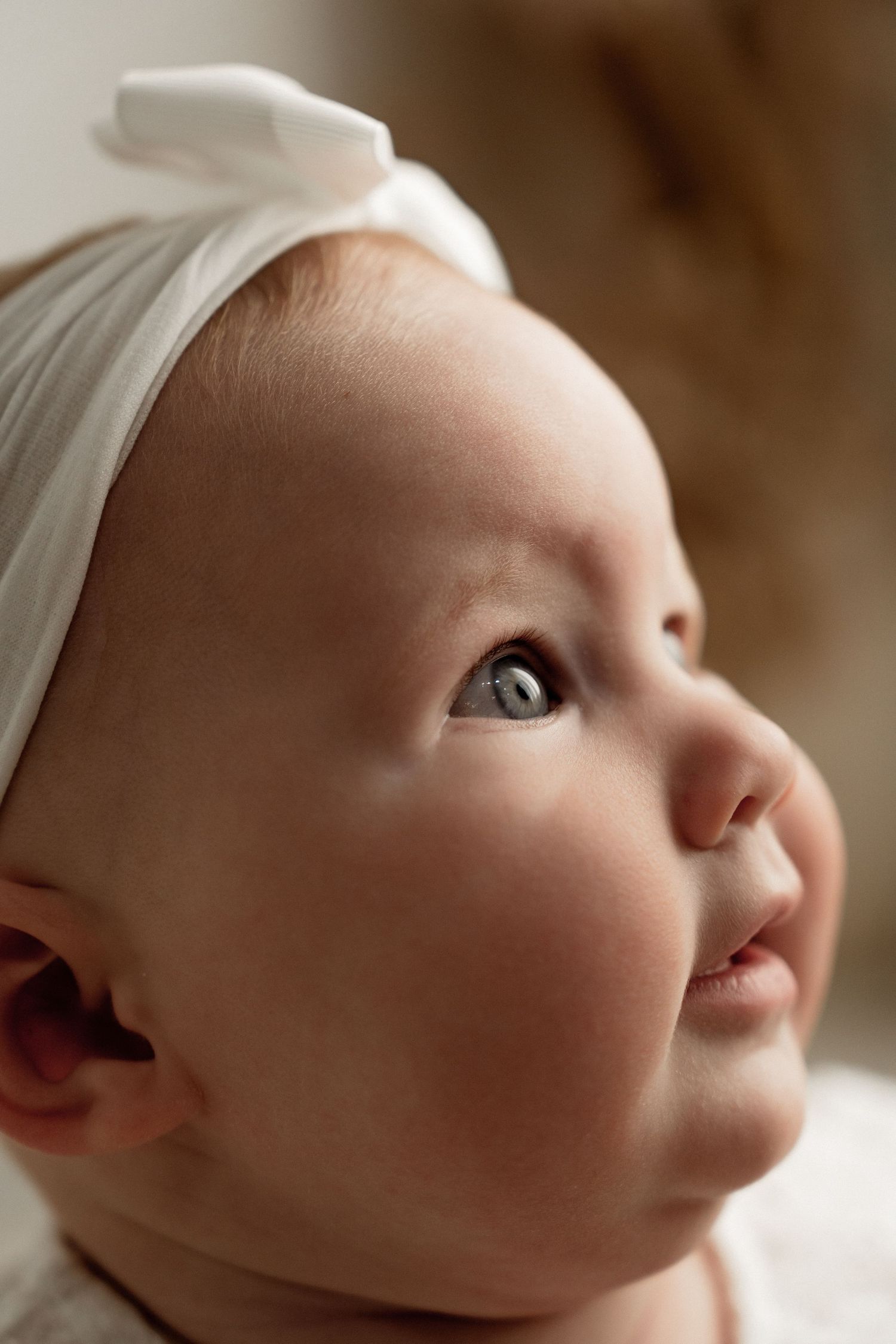 Close-up artistic profile shots of a baby's face wearing a white bonnet against a soft neutral background.