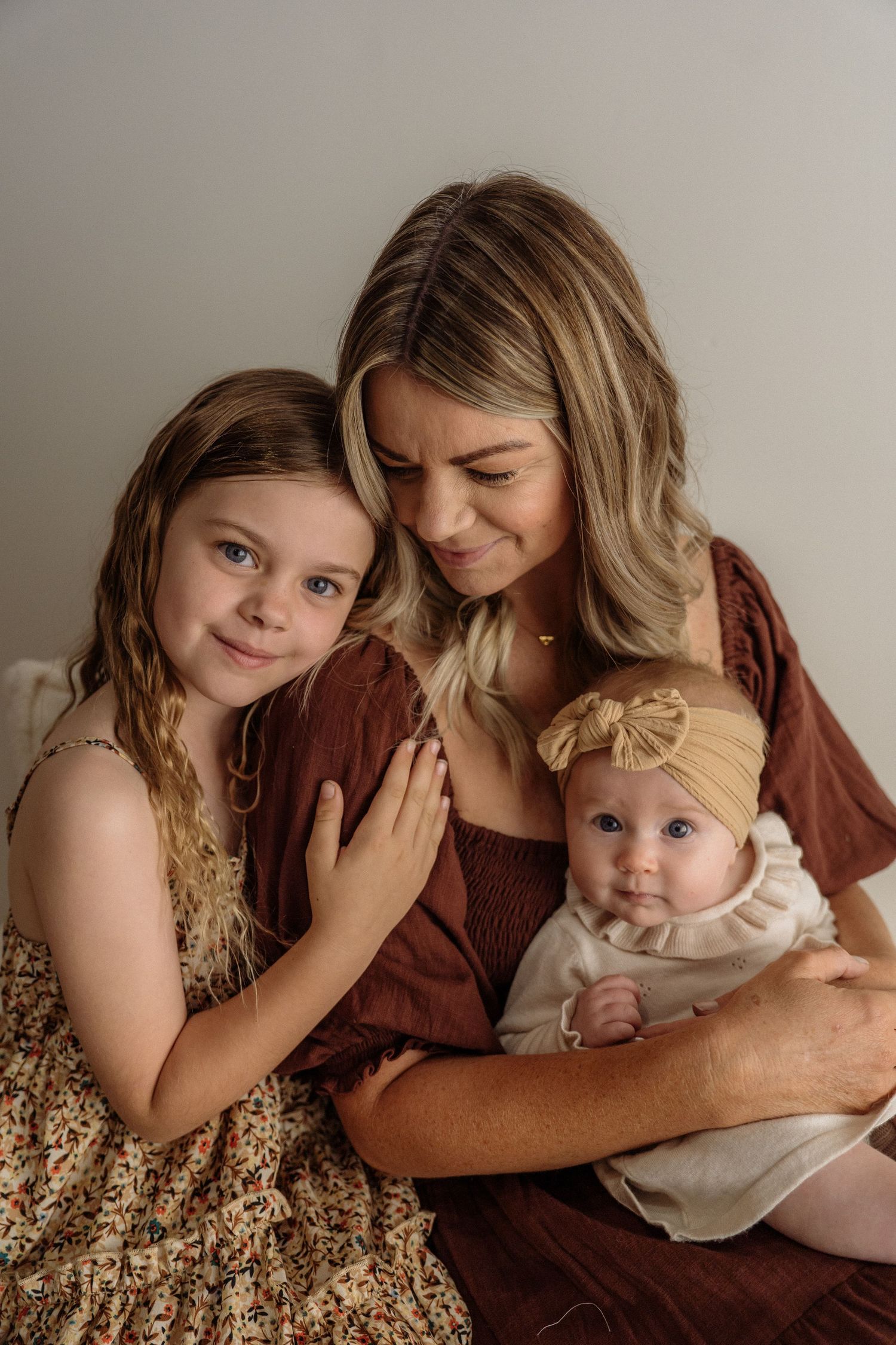A tender series of family portraits showing intimate moments of affection between parent and children in matching warm tones.