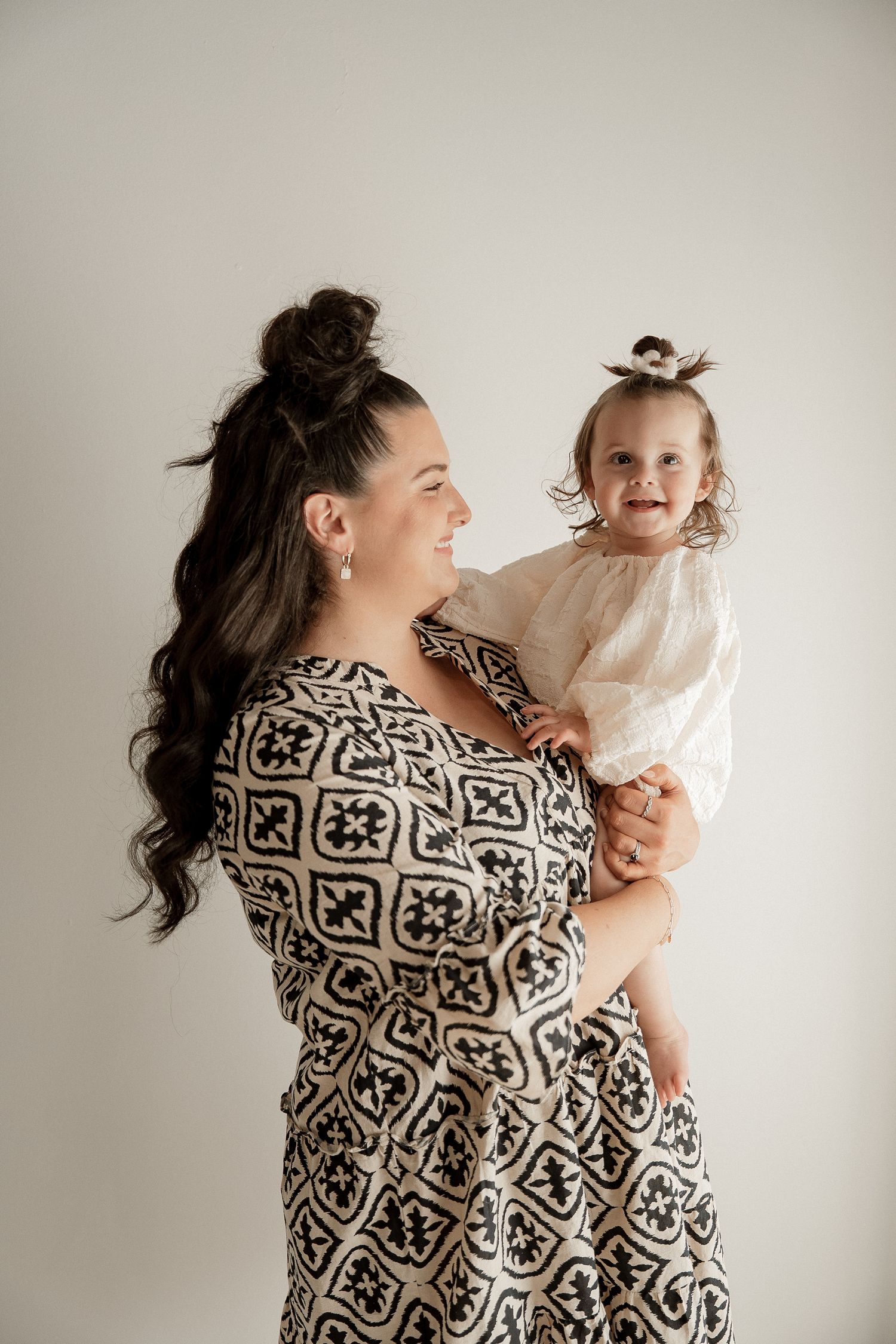 A series of candid moments showing tender interaction between parent and baby against a neutral backdrop.