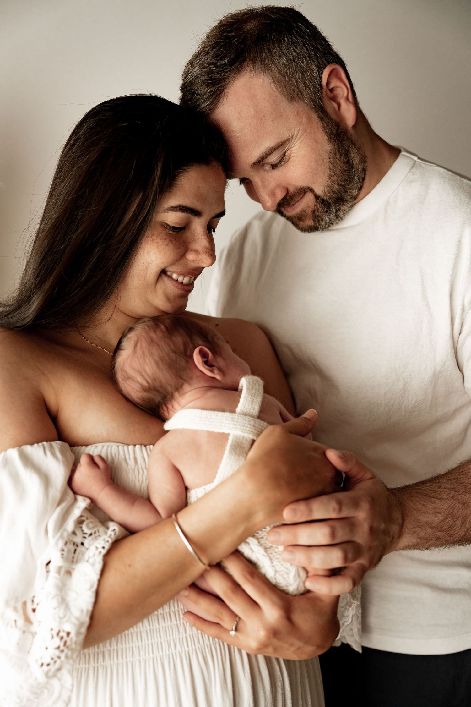 A couple shares an intimate moment while bottle feeding their newborn baby in a series of tender photographs.