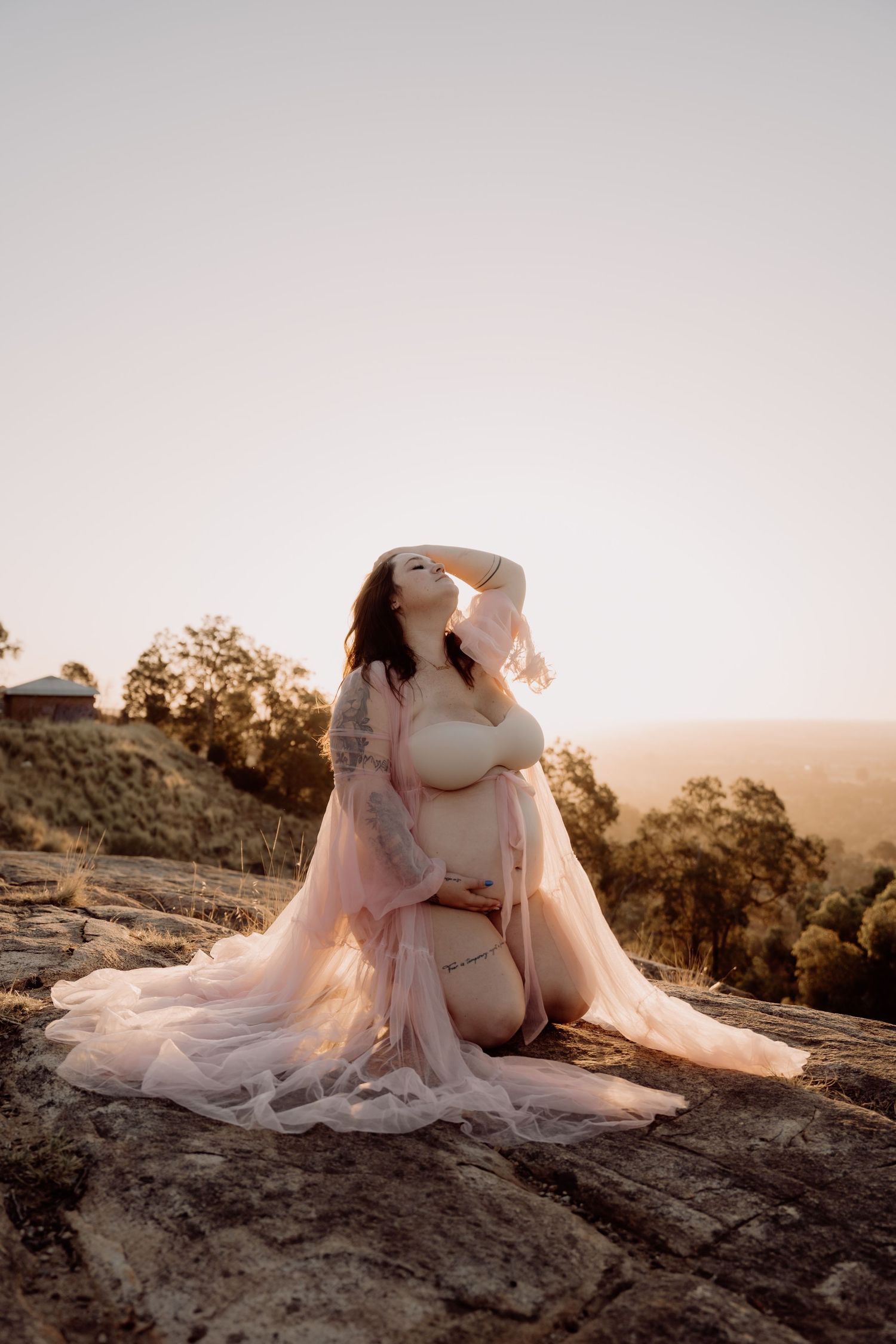 Ethereal sunset maternity photo session showing a flowing white dress against rugged mountain terrain and golden light.