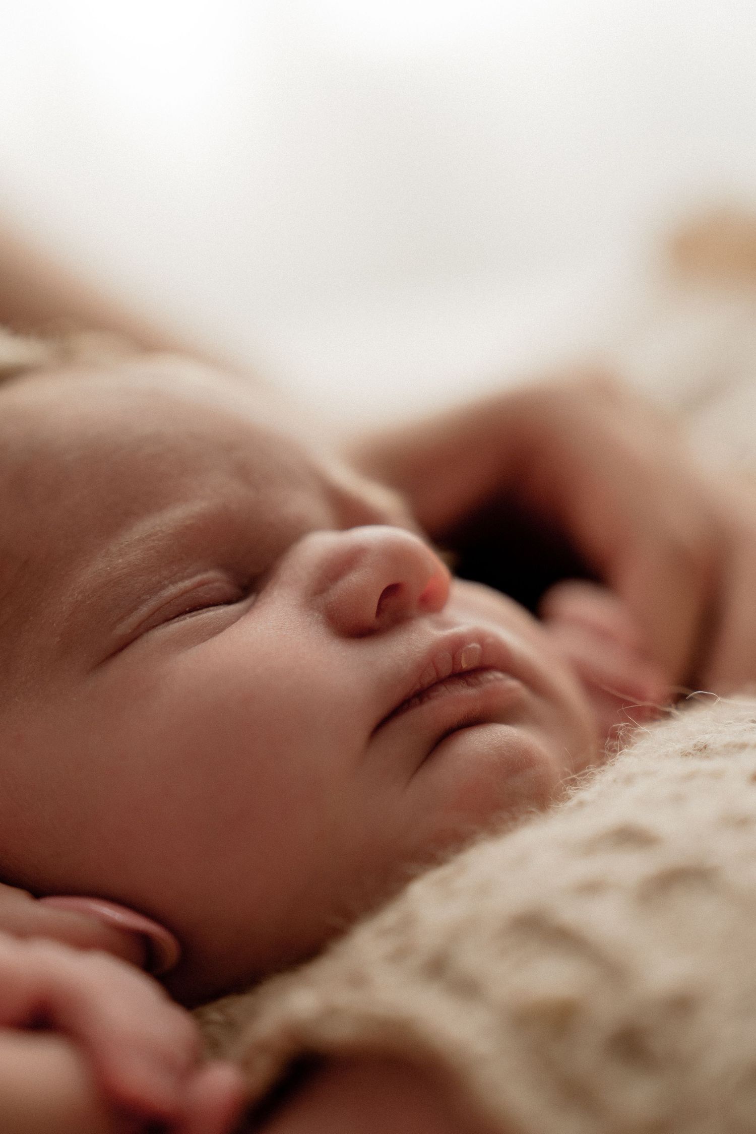 Close-up of a peaceful sleeping baby against a soft white fabric background.