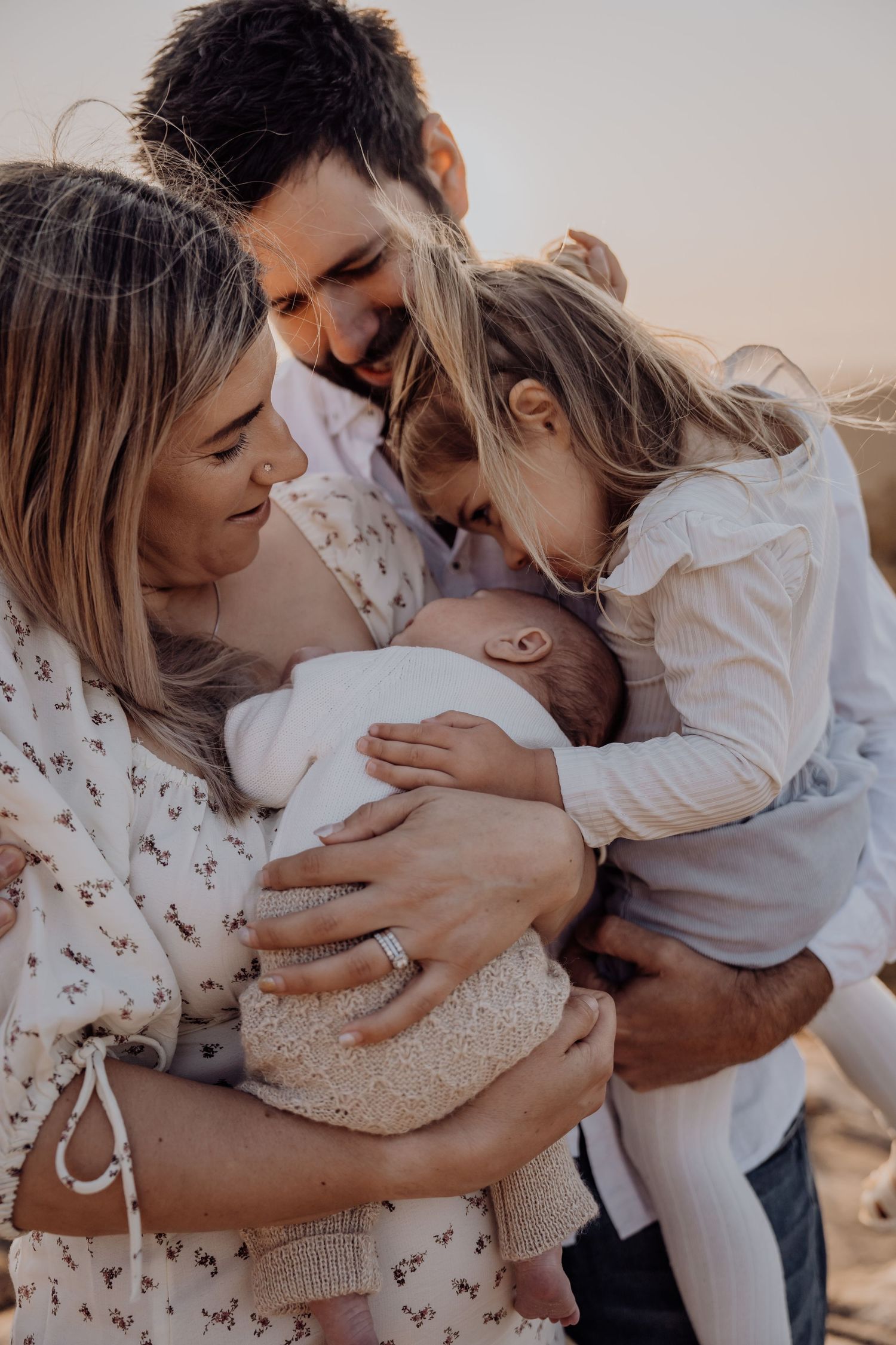 Tender family moment at sunset showing affectionate embrace in warm neutral tones.