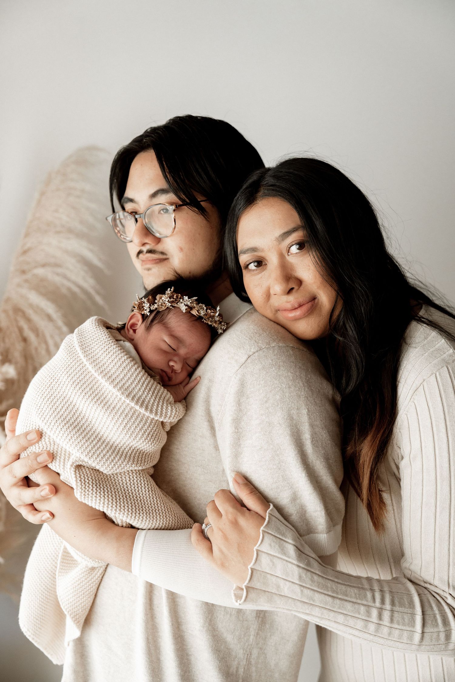 Two people wearing cozy cream-colored sweaters embrace in a series of intimate portrait photos against a light background.
